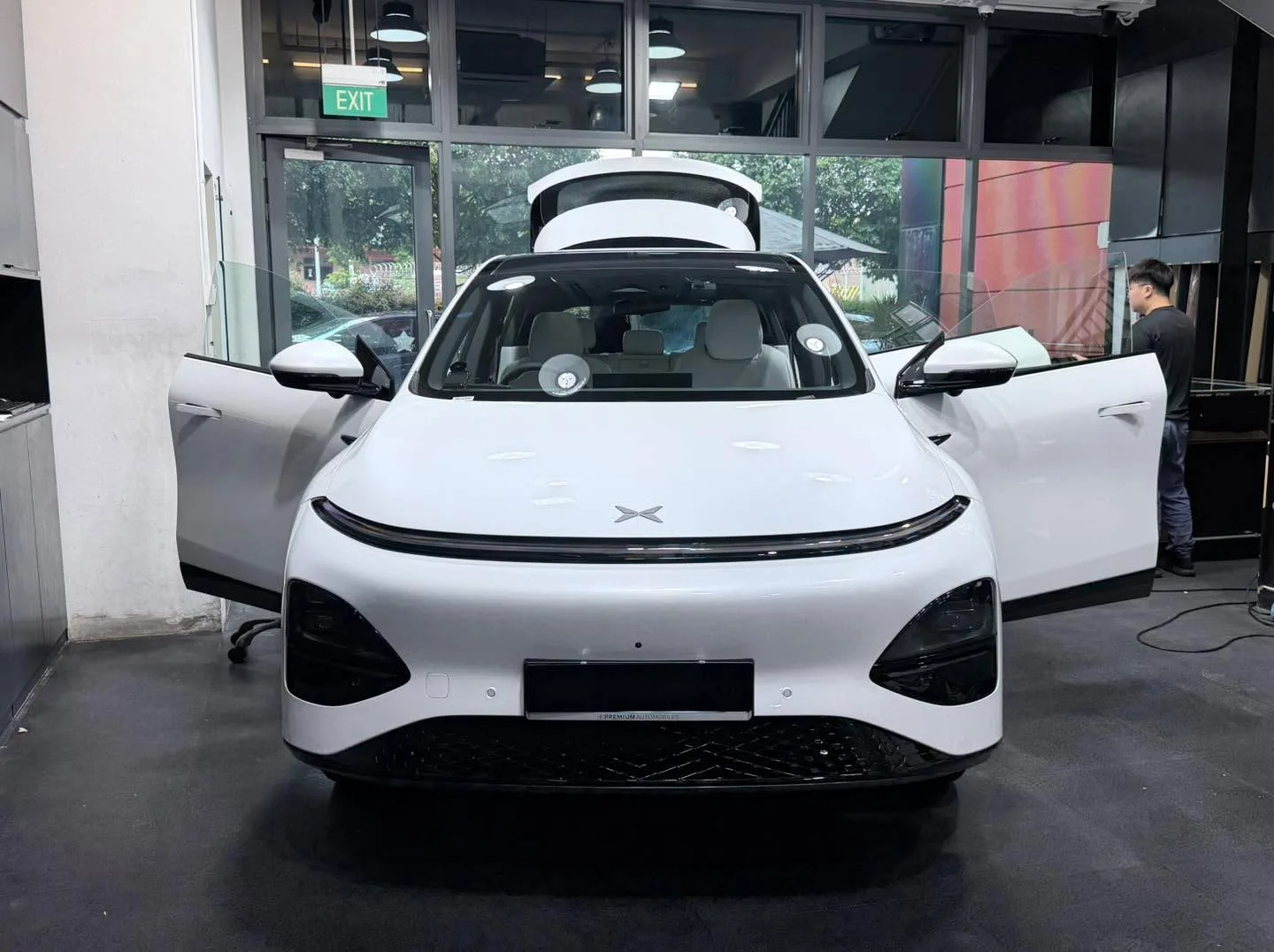A white Tesla with doors open and a white BMW X3 behind it.