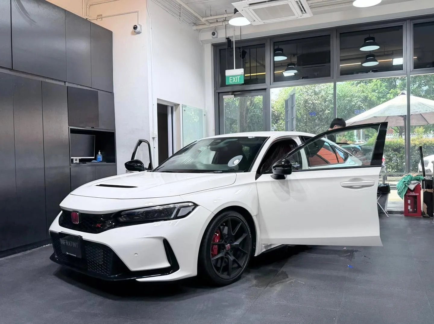 A white car with an open roof and doors open inside the workshop.