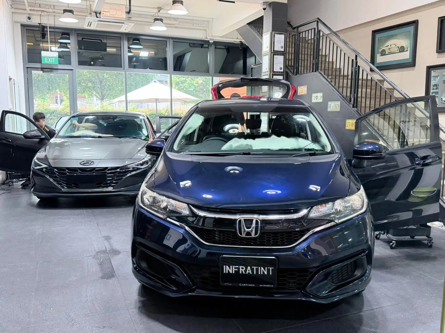 A dark blue Honda and a silver Hyundai Avante sedan indoors, viewed from the front.