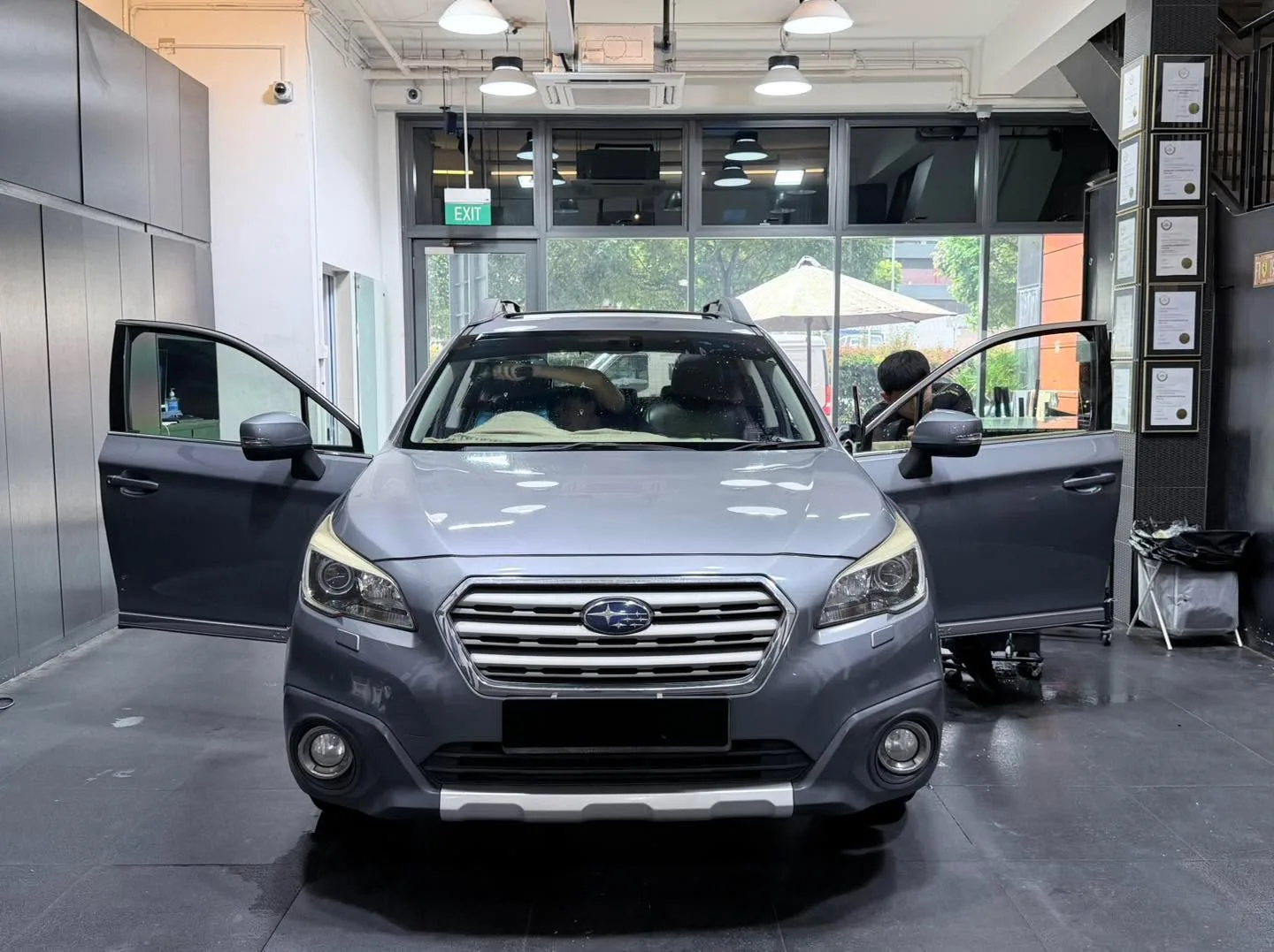 A silver Honda Civic compact car with both doors open, viewed from the front in the workshop.