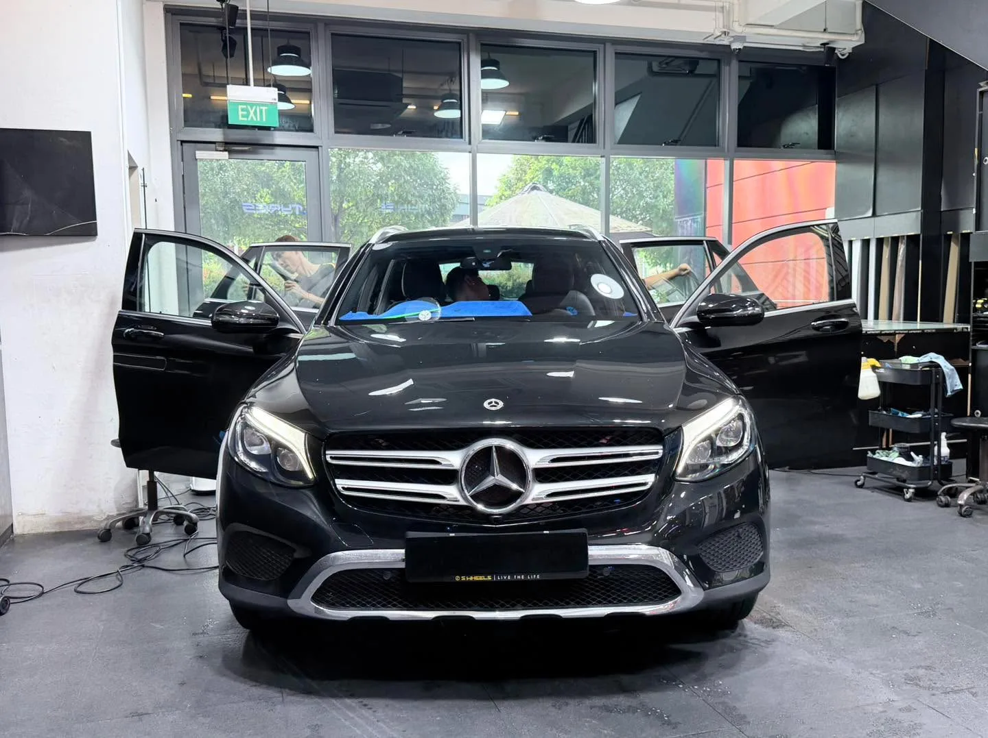 A black Mercedes-Benz SUV with its door open during tinting in the workshop.