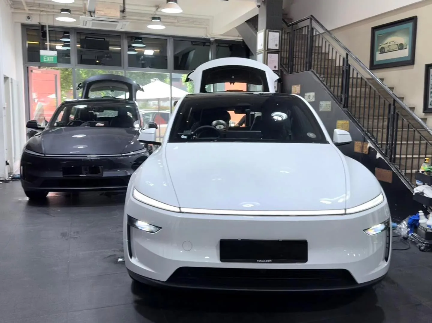 A white Tesla sedan viewed from the front inside the workshop.