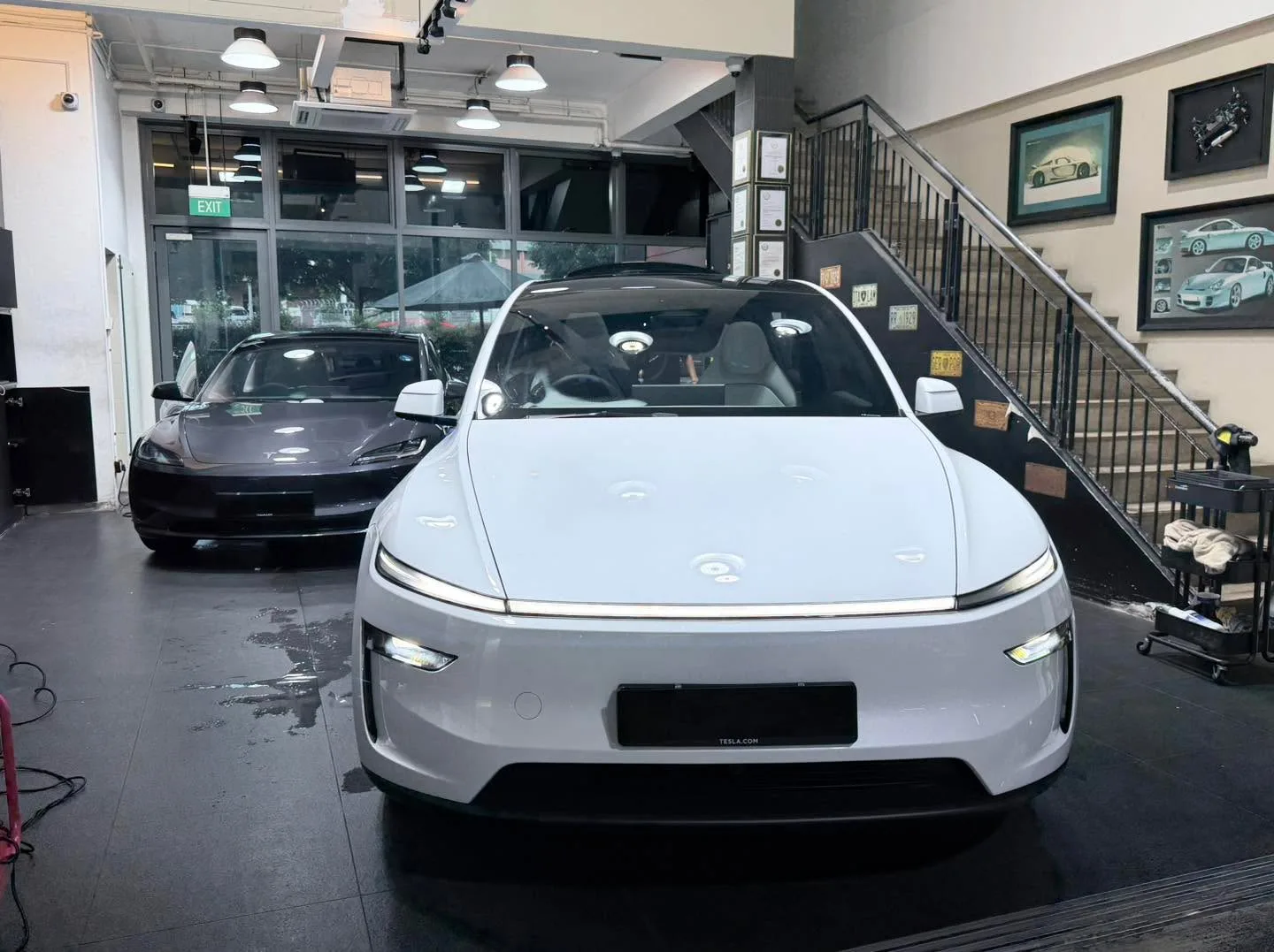 A white Tesla sedan viewed from the front inside the workshop.