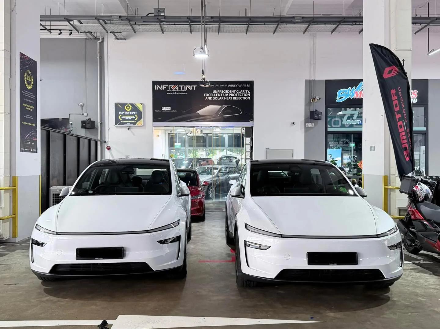 Two white Tesla Model Y vehicles parked side by side in the workshop.