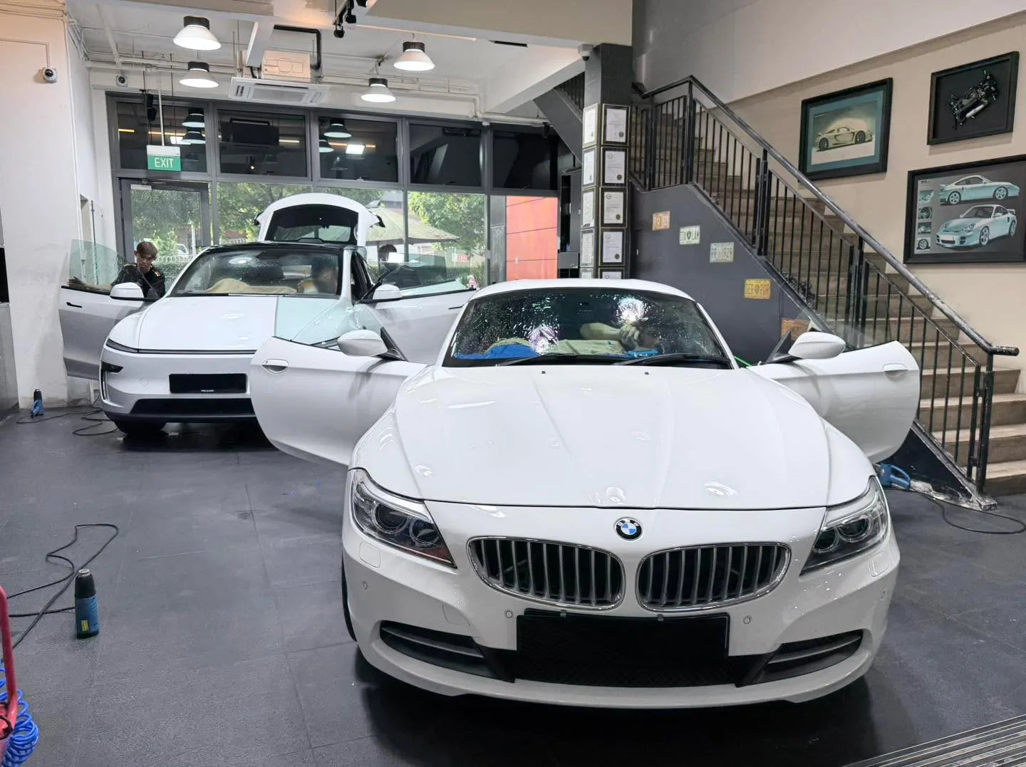 A white BMW convertible with the top down, parked inside the workshop.