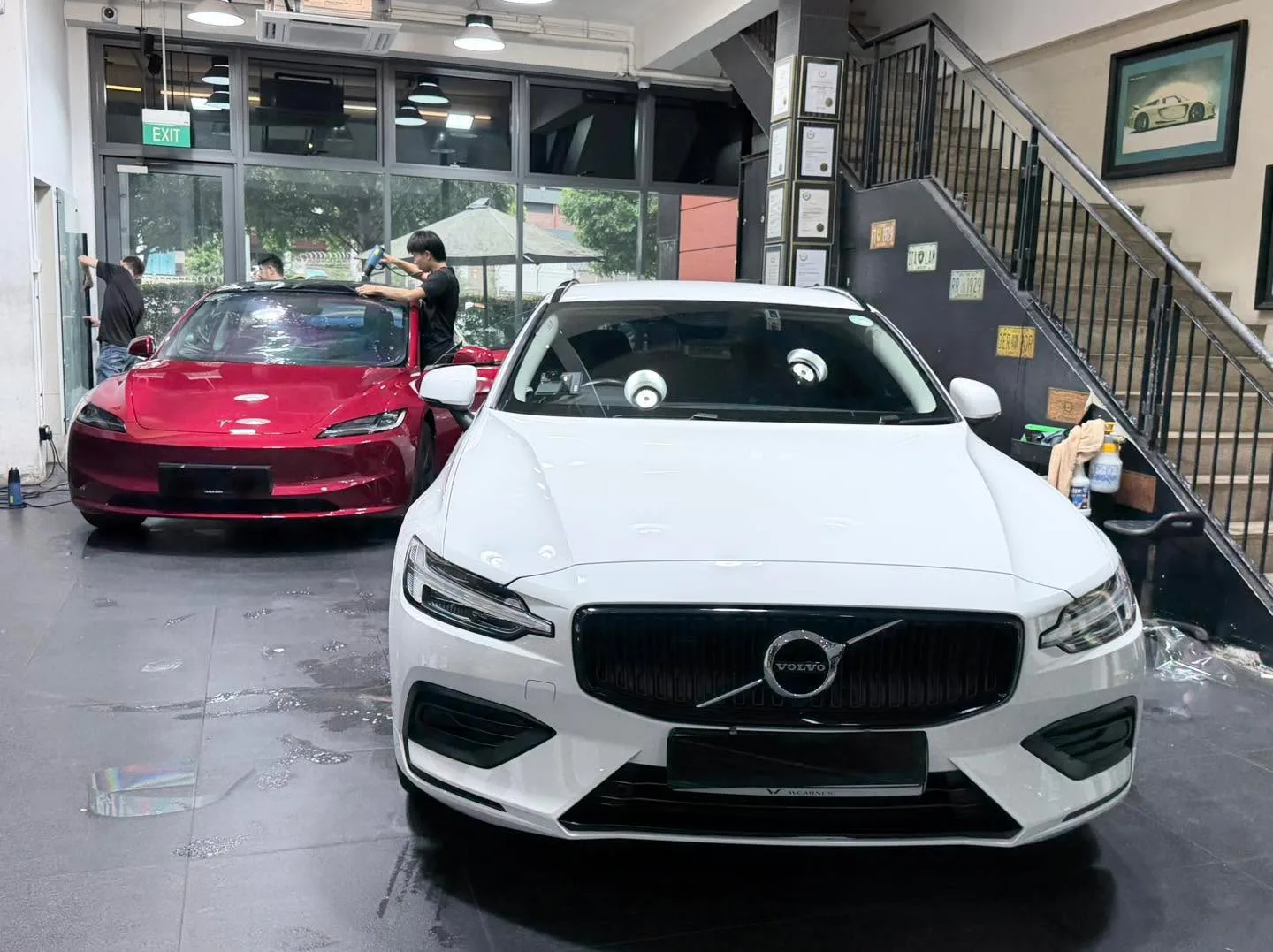 A white BMW convertible, a white Tesla sedan, and a dark Toyota Alphard at the workshop.