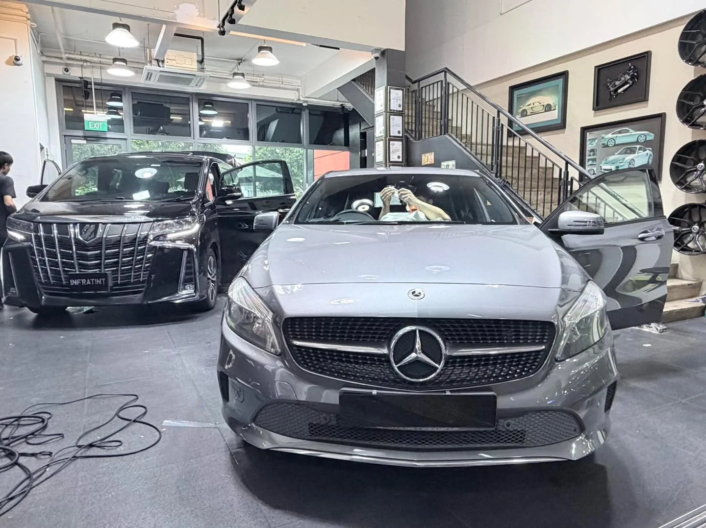 A silver Mercedes-Benz sedan and a red Tesla in the workshop.