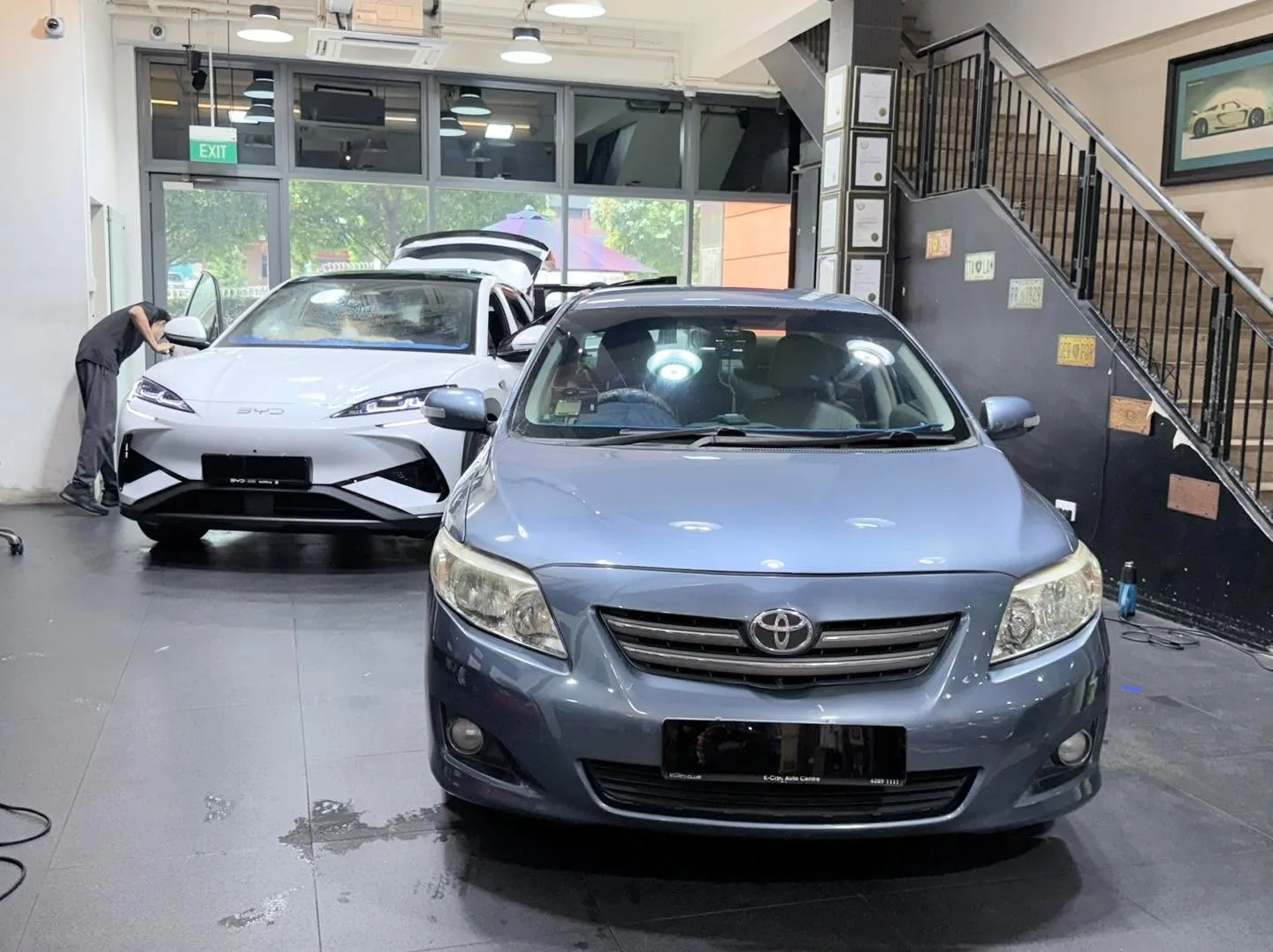 A white Mercedes-Benz GLC and a silver Toyota sedan in the workshop.