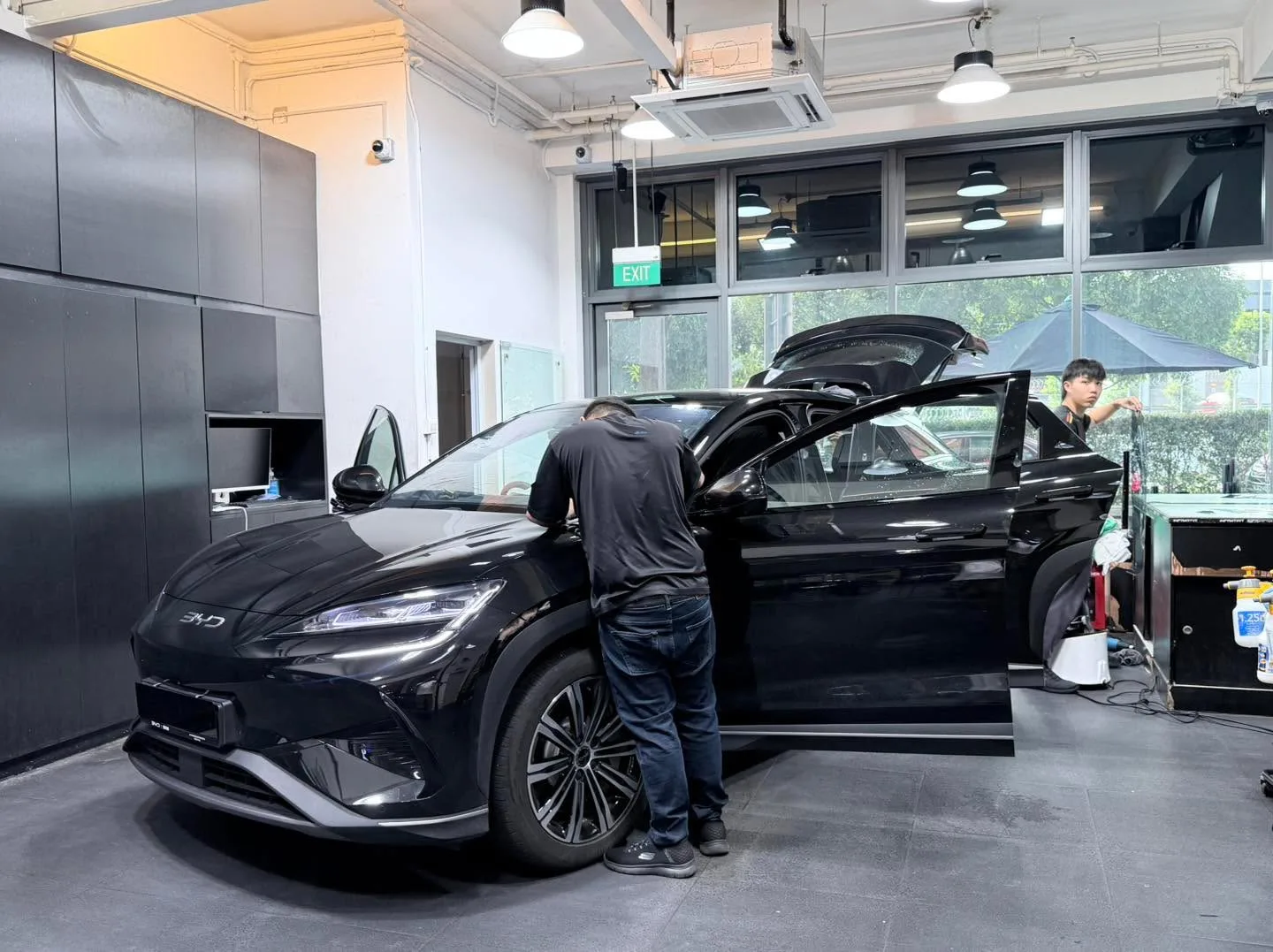A black BYD Sealing 7 with doors open during the tinting process.