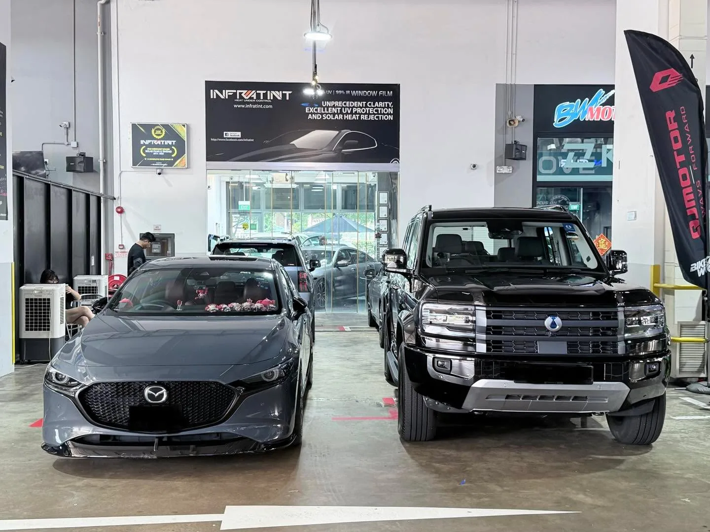 A grey Mazda sedan and a black pickup truck parked in the workshop.