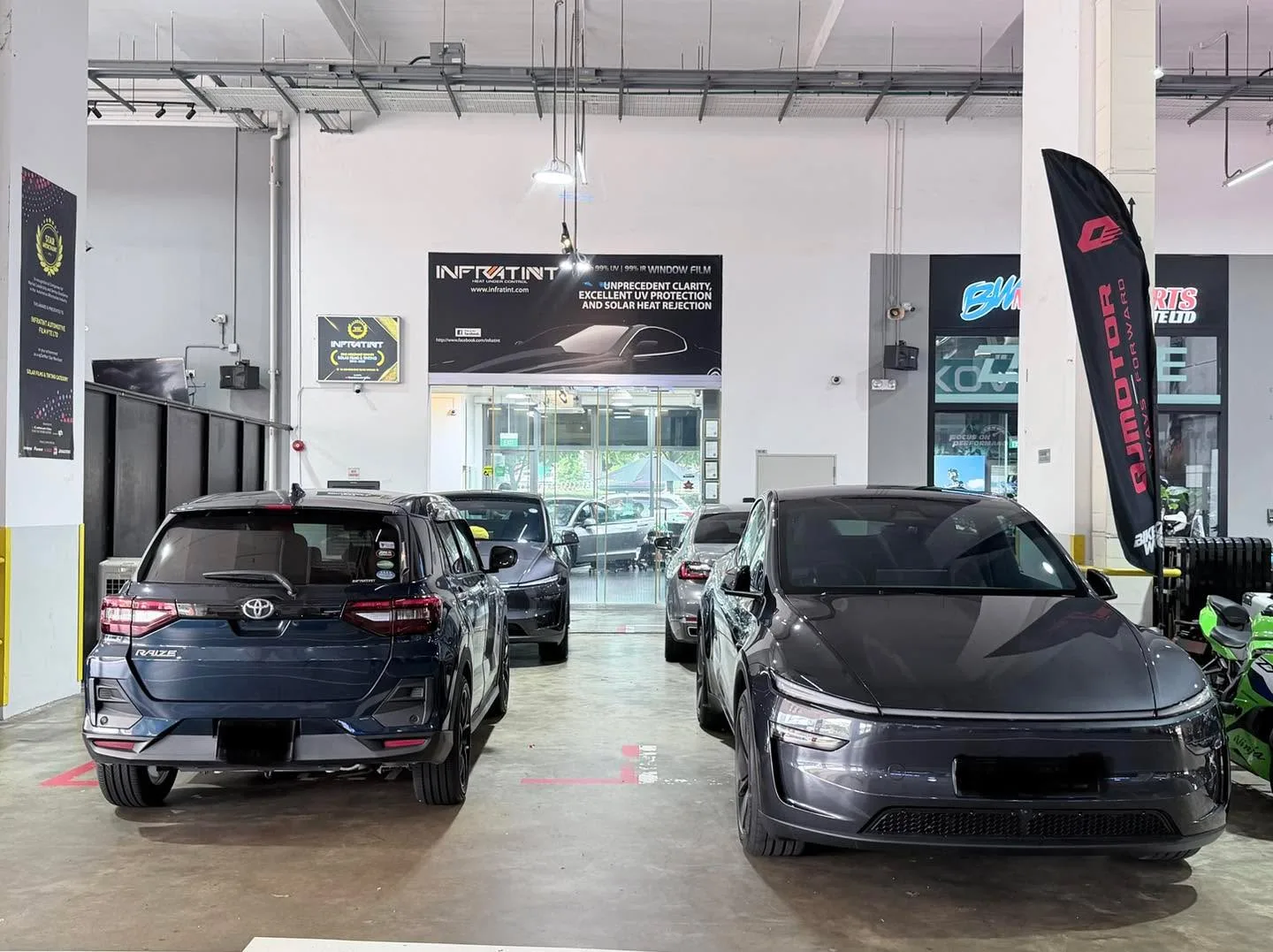 A dark blue Toyota SUV and a dark grey sedan parked in the workshop.