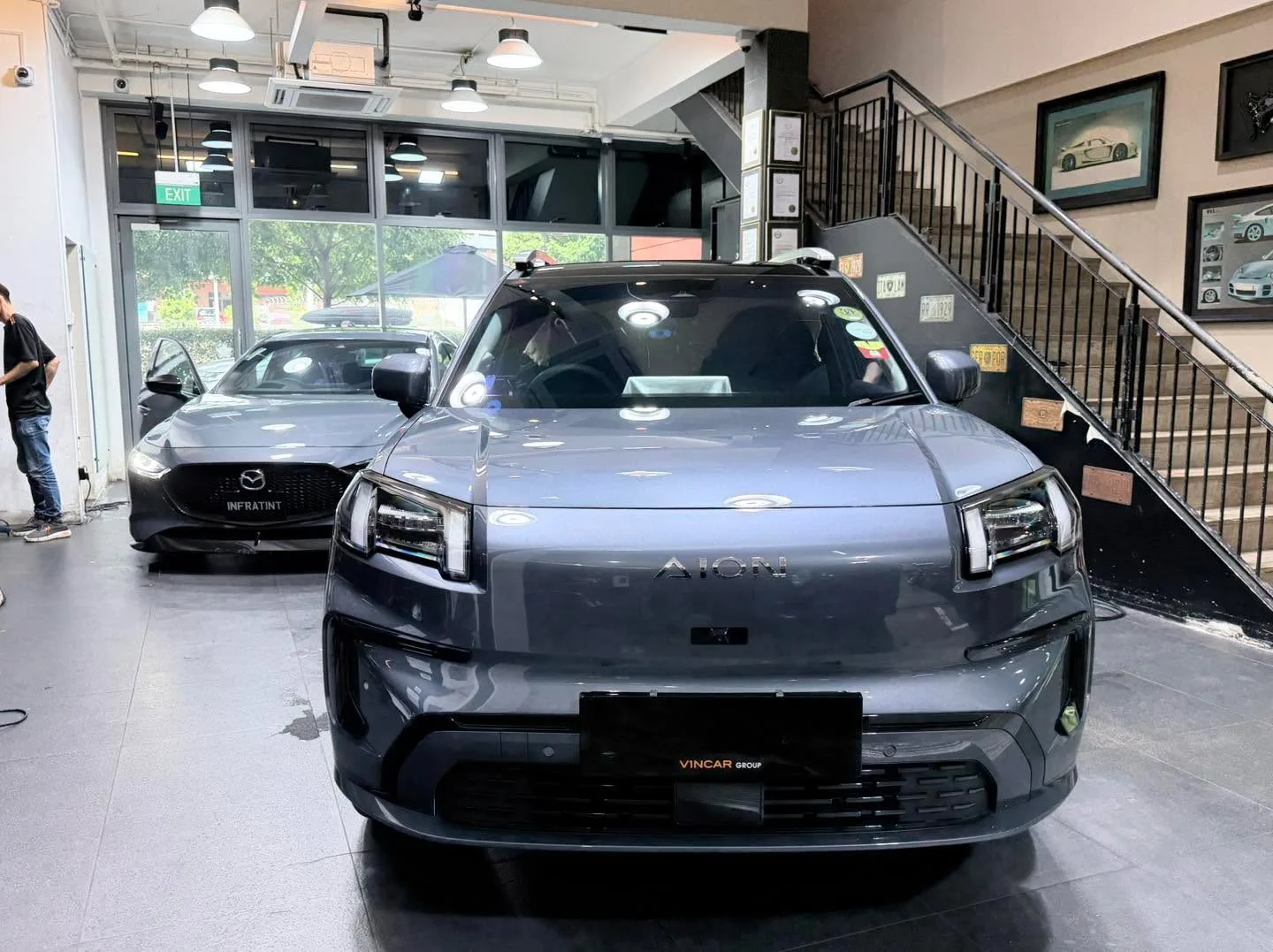 A grey BMW sedan and a dark grey sedan parked in the workshop interior.
