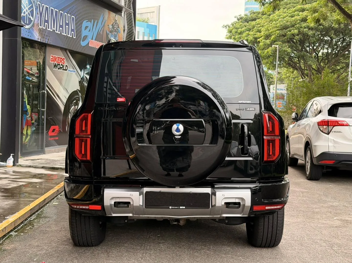 The rear view of a black Denza B5 with a spare tyre mounted, showing the tinted rear window and red tail lights.