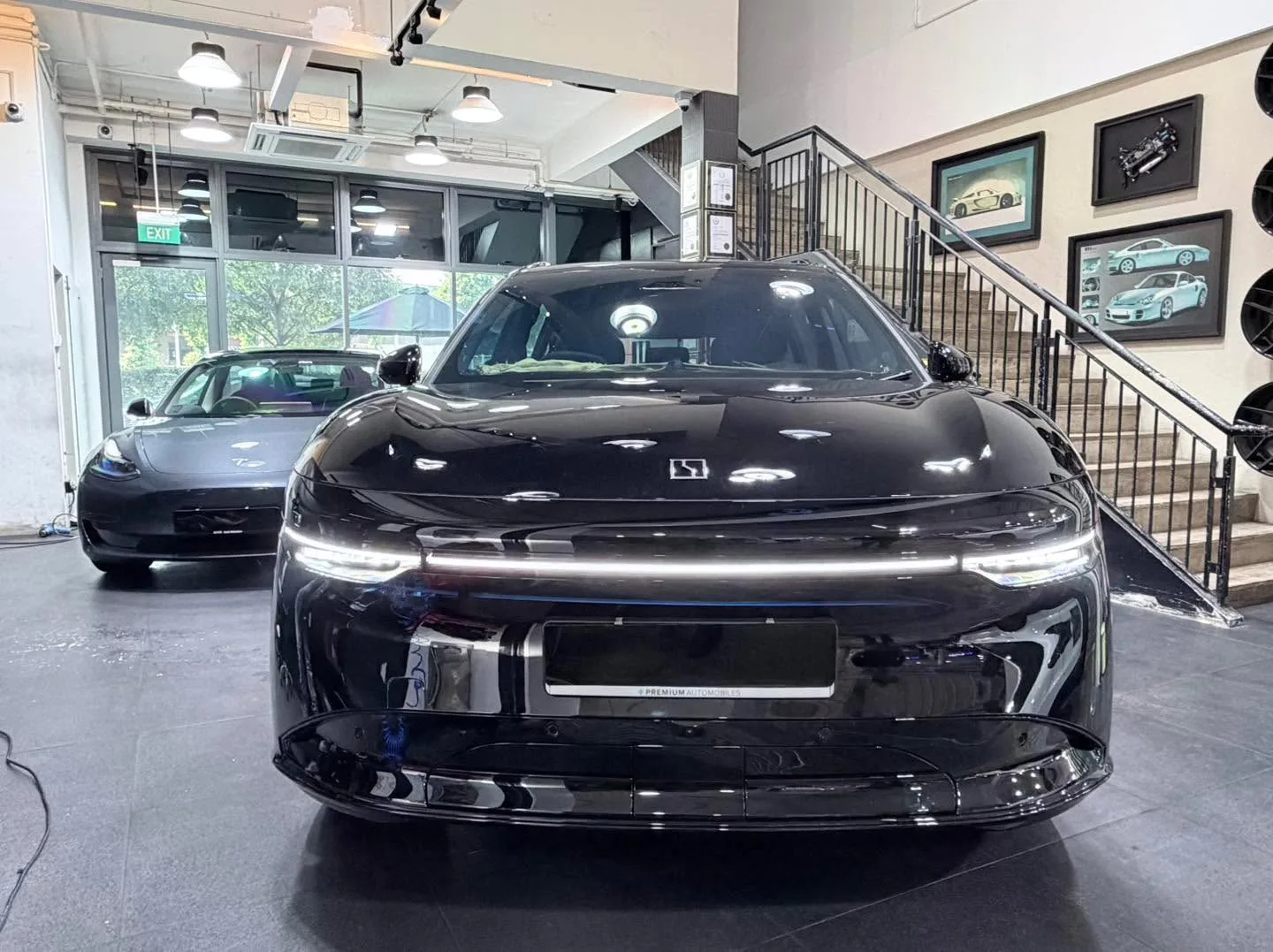 A black Peugeot SUV with LED daytime running lights viewed from the front, with a Tesla visible behind.