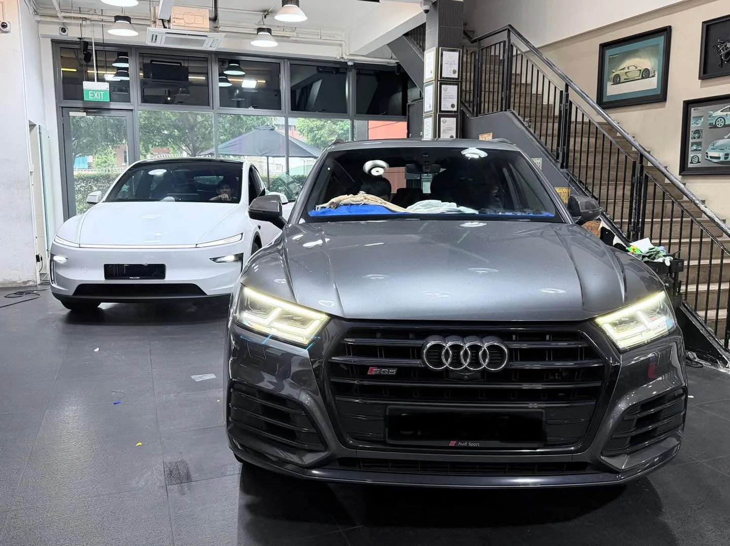 A dark grey Audi Q5 SUV with LED headlights and a white Tesla partially visible on the left.