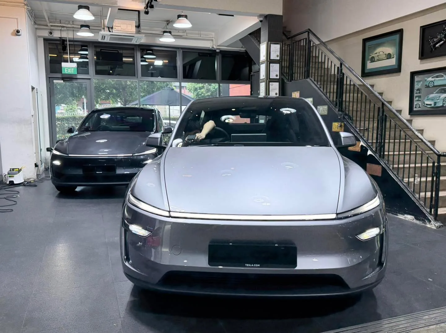 A dark-coloured Tesla and white BYD Sealing 7 parked in the workshop.