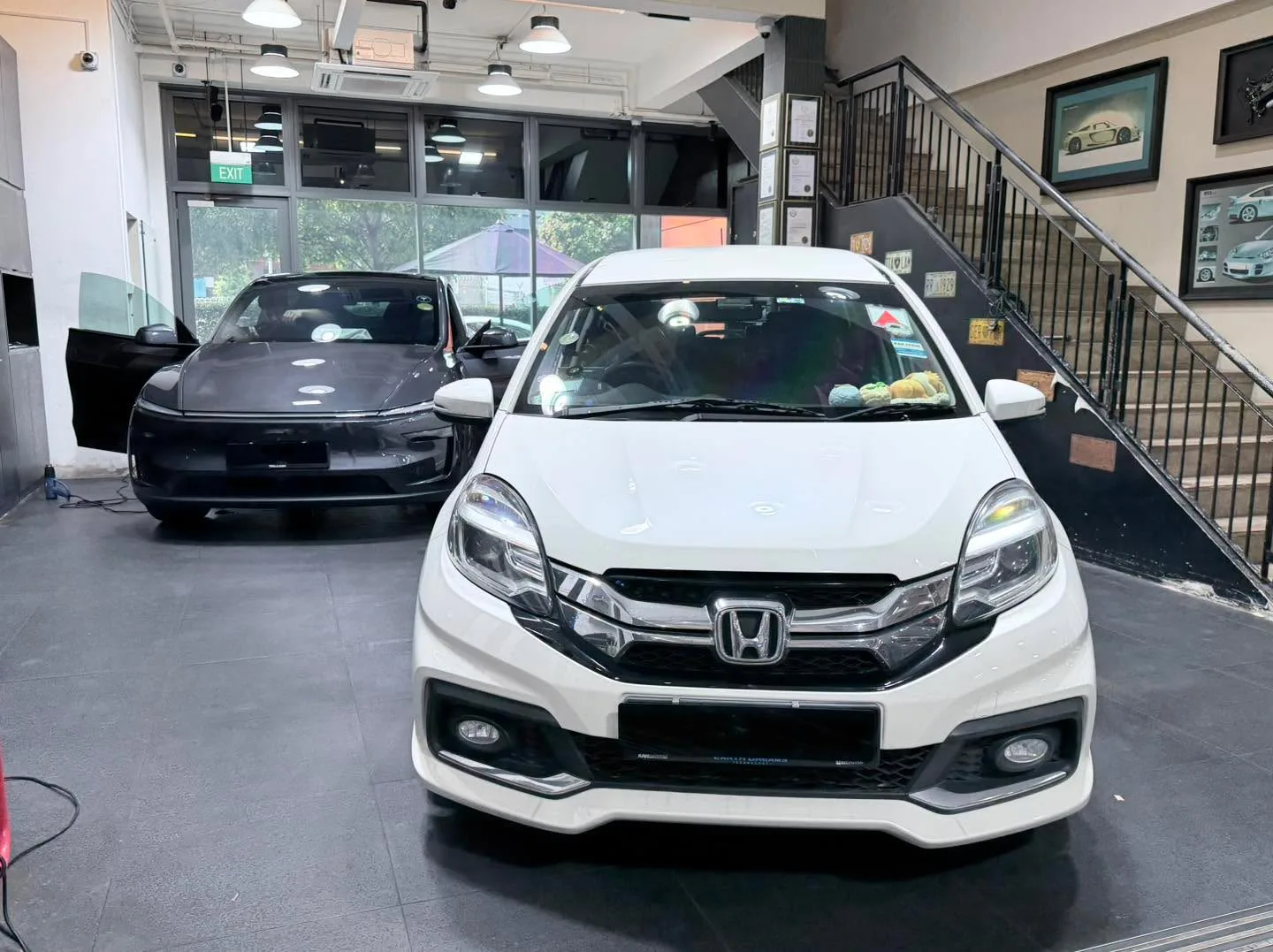A white Honda Mobilio parked indoors with a dark saloon behind it.