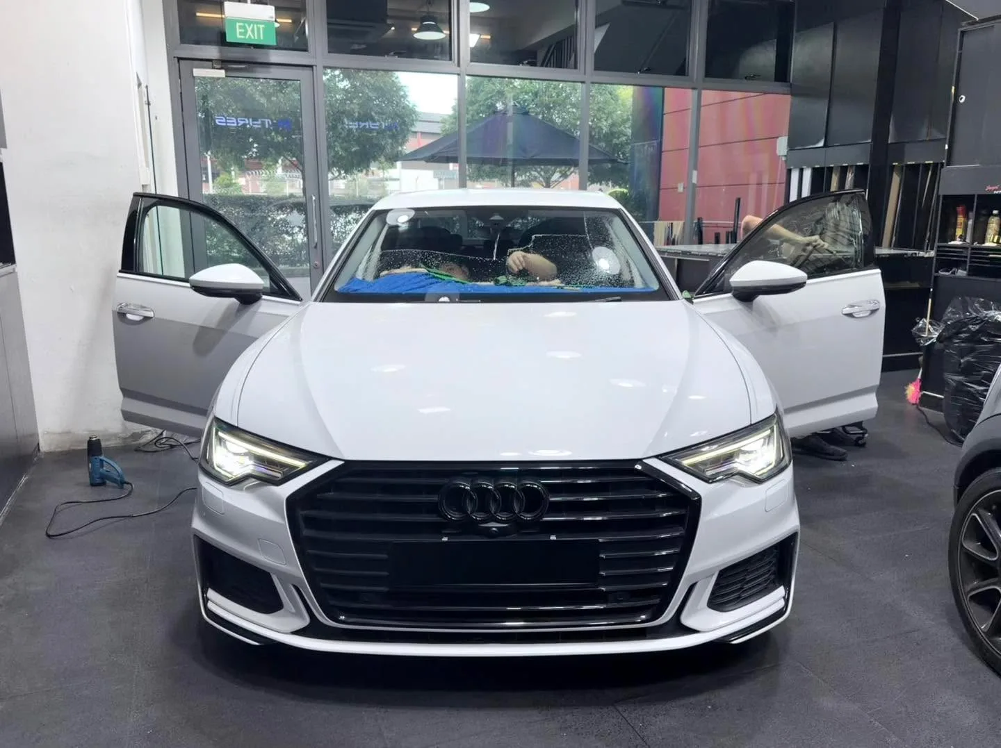 A white Audi A6 saloon with doors open during window tinting work.