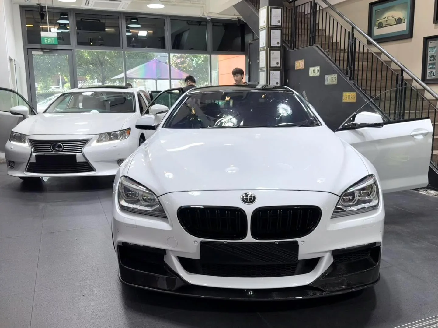 A white BMW saloon with prominent kidney grille facing the camera in an indoor showroom.