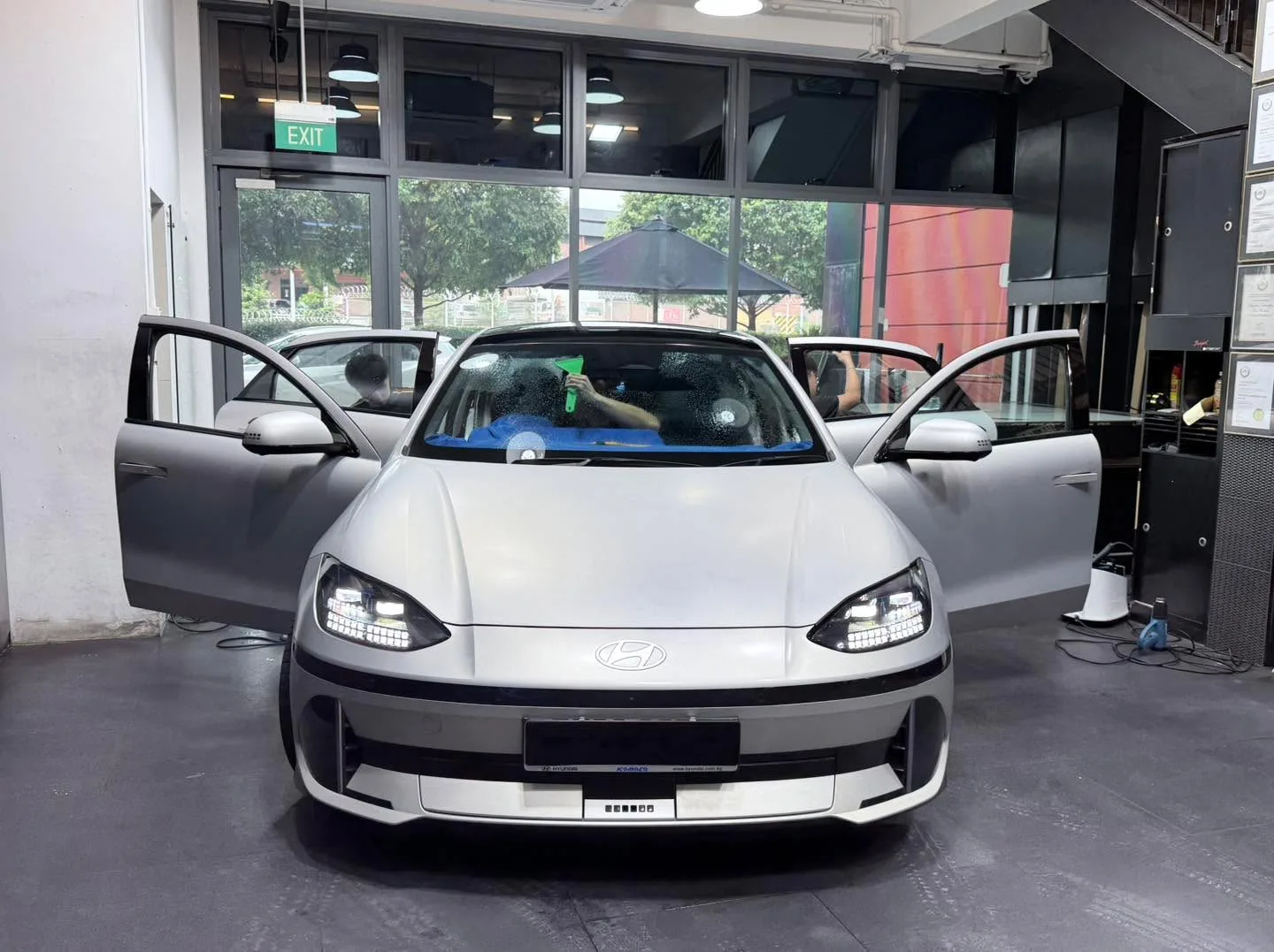 A white Hyundai Ioniq 6 electric sedan with doors open in the workshop.
