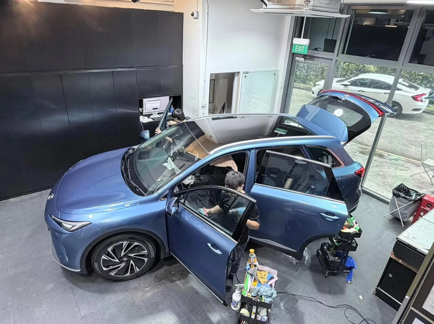 A blue Zeekr 7X with bonnet and doors open in the workshop.