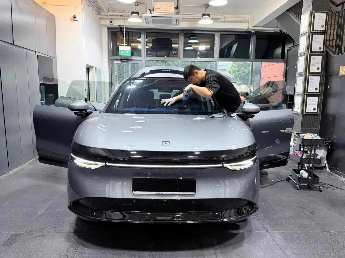 A grey saloon with a technician working on its windscreen.