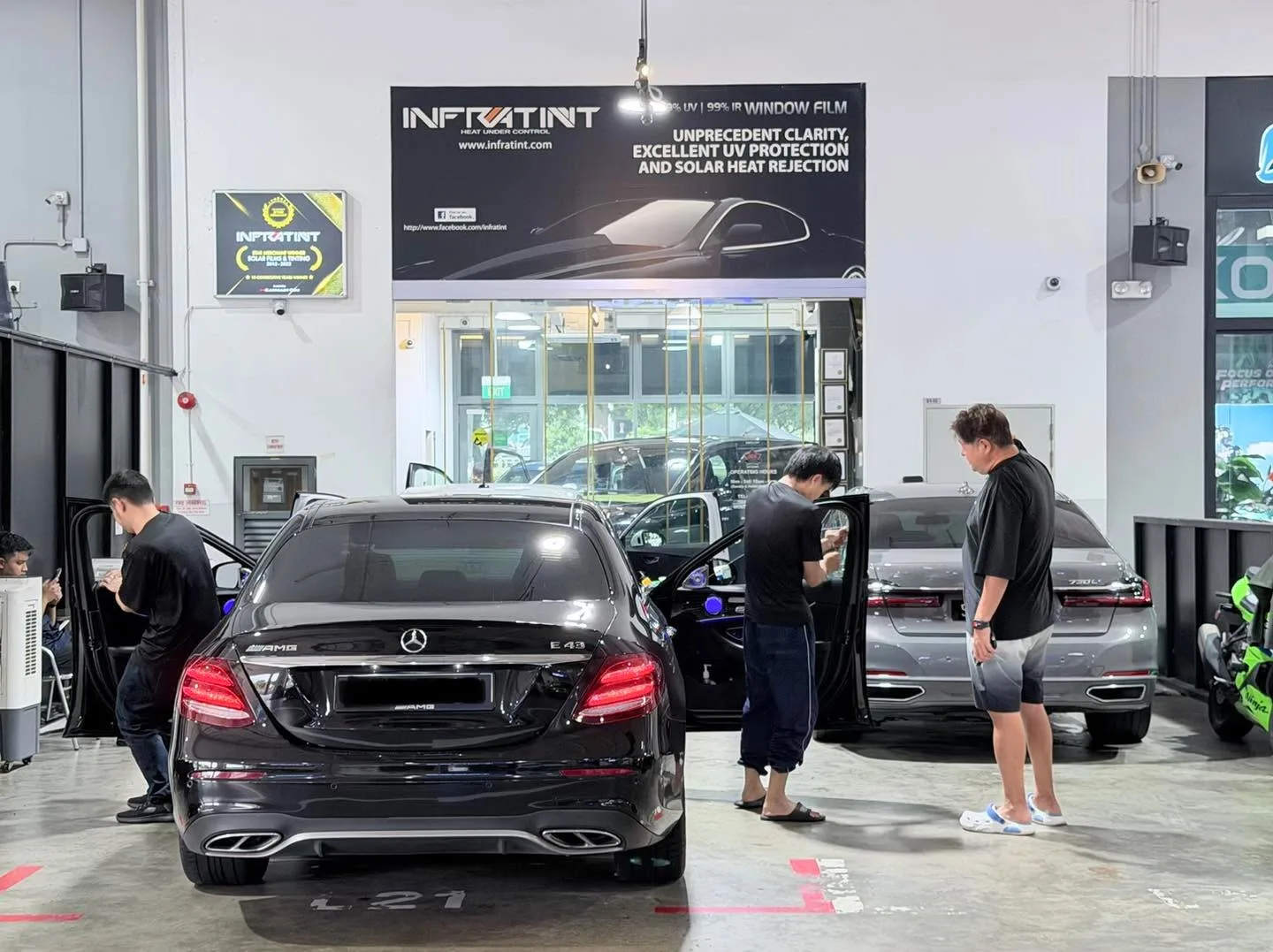 Black Mercedes-Benz sedan with technicians working on the windows inside the workshop.