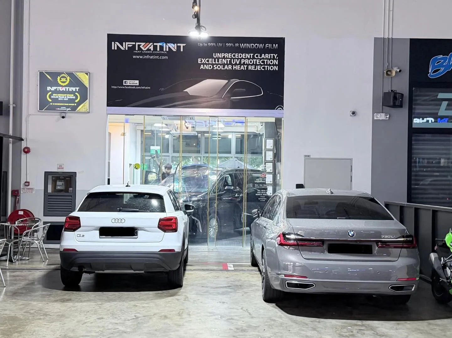 White Audi Q2 compact SUV and silver BMW sedan parked outside the workshop.