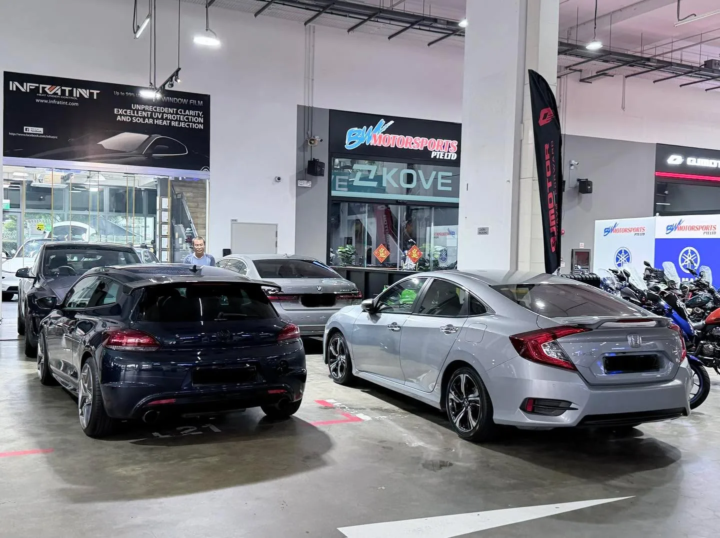 A dark blue Honda Civic and a silver Honda Civic saloon parked indoors at the workshop.