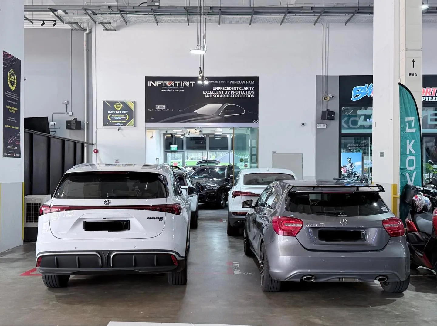 A white MG S6, a silver Mercedes-Benz A200, and other vehicles at the rear of the workshop.