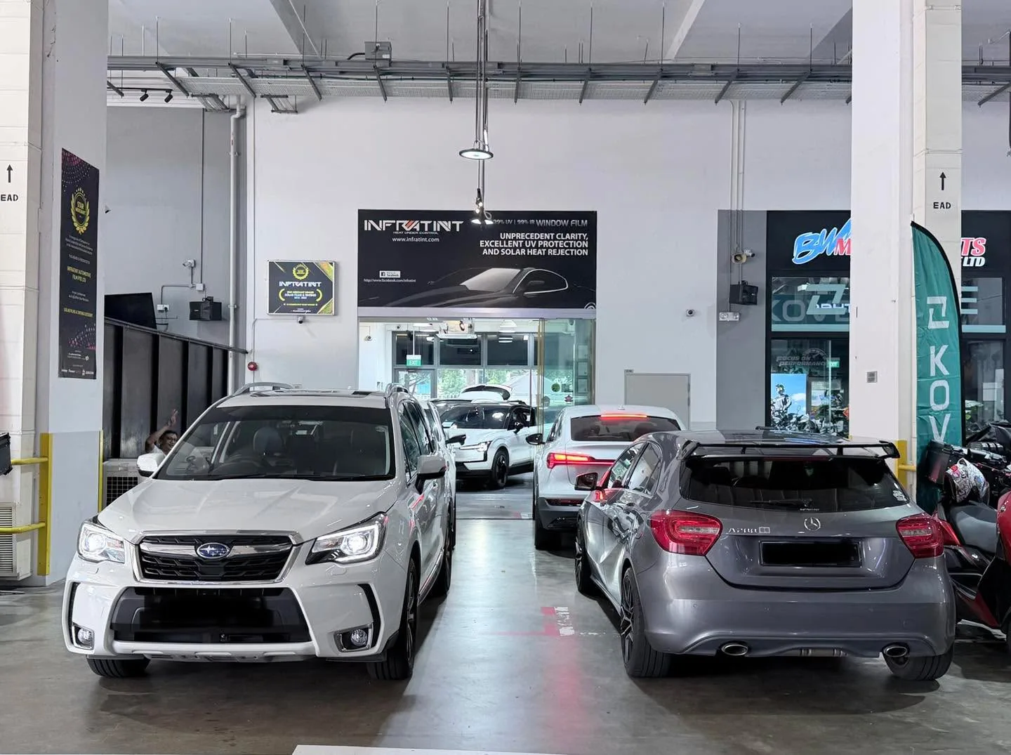 A white Subaru Forester and silver Mercedes-Benz A200 parked in the workshop.