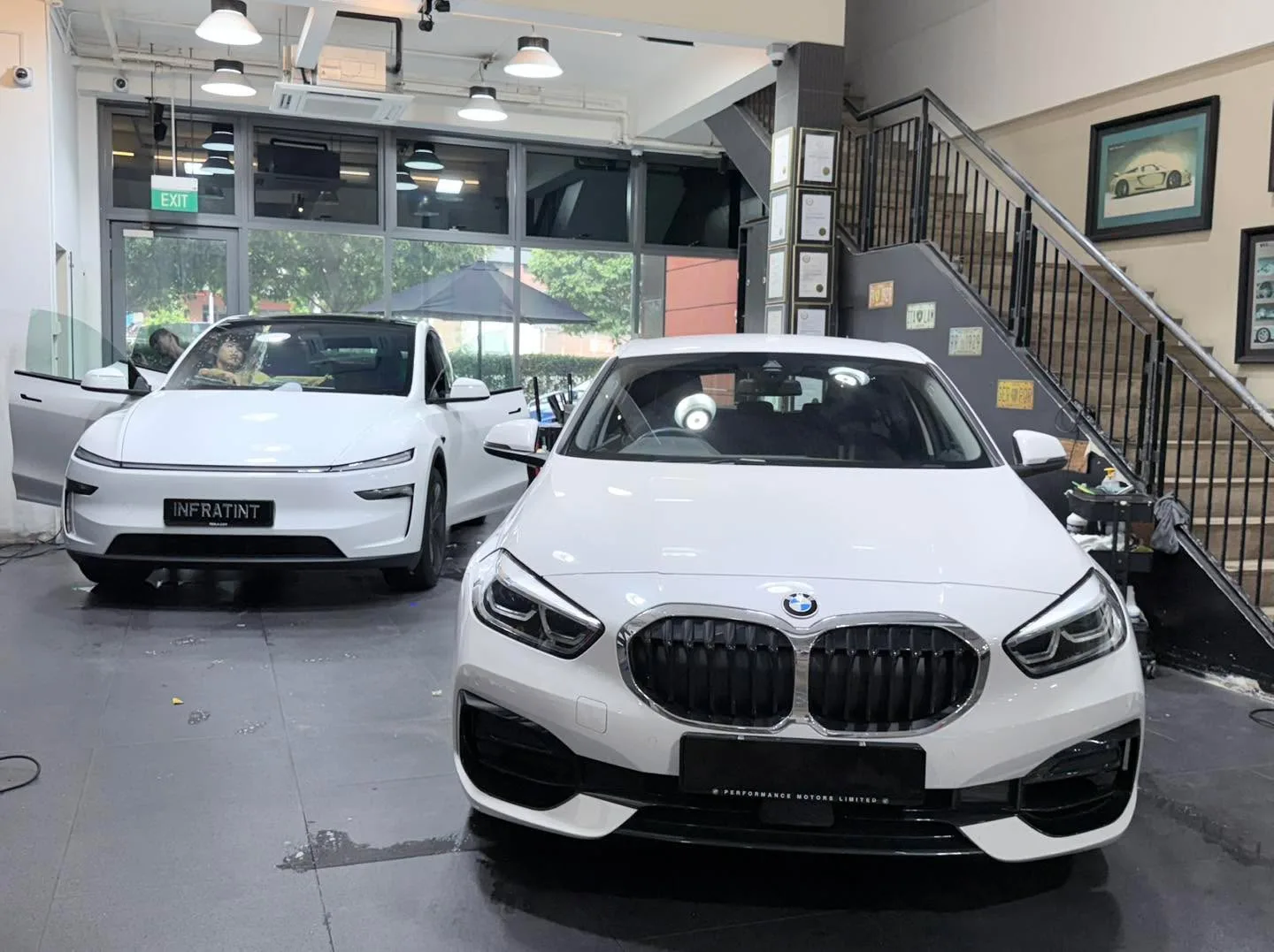 A white Toyota Harrier and white Volvo EX30 parked in the workshop.