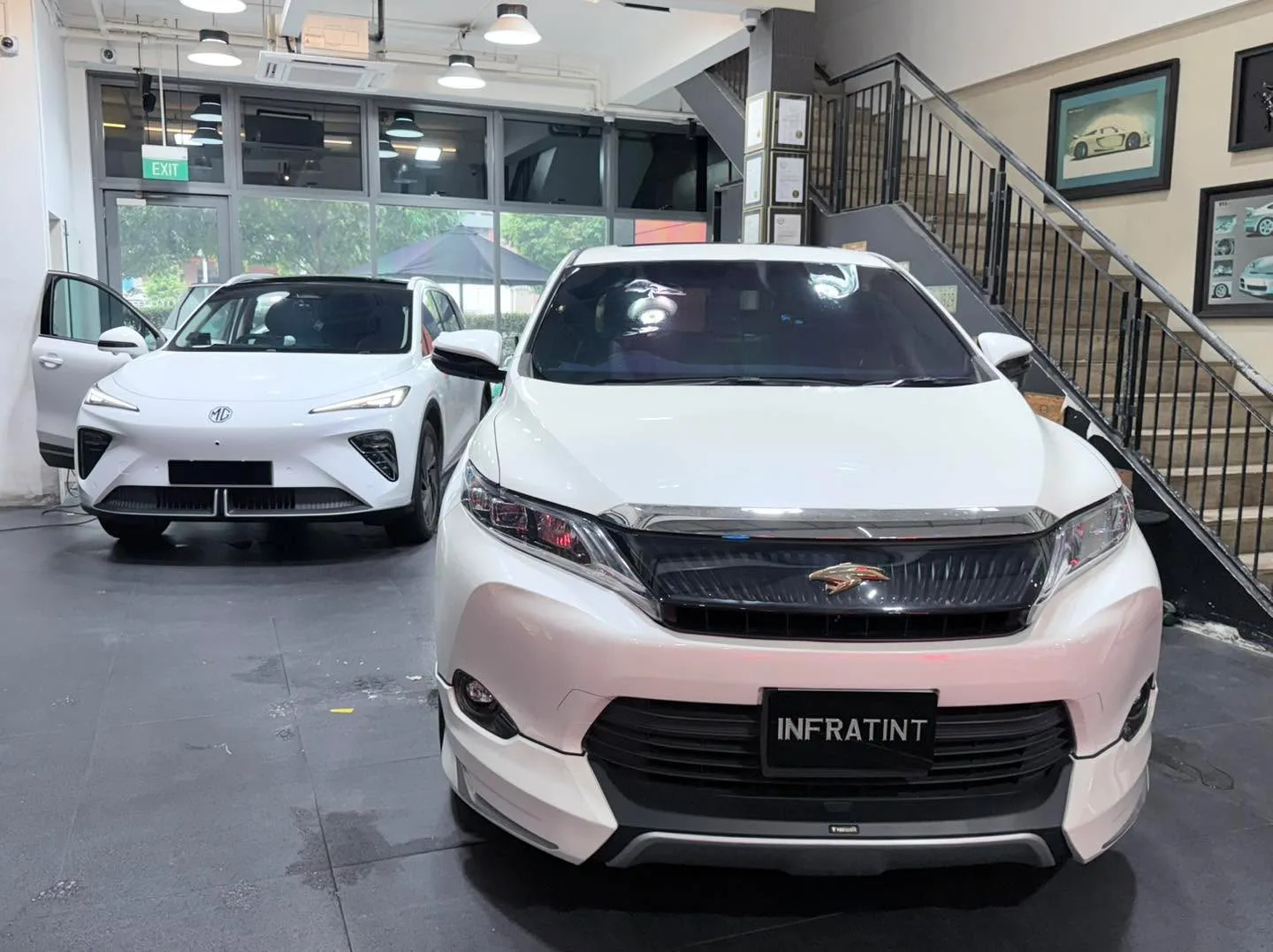 A white BMW 116 and white MG S6 parked side by side in the workshop.