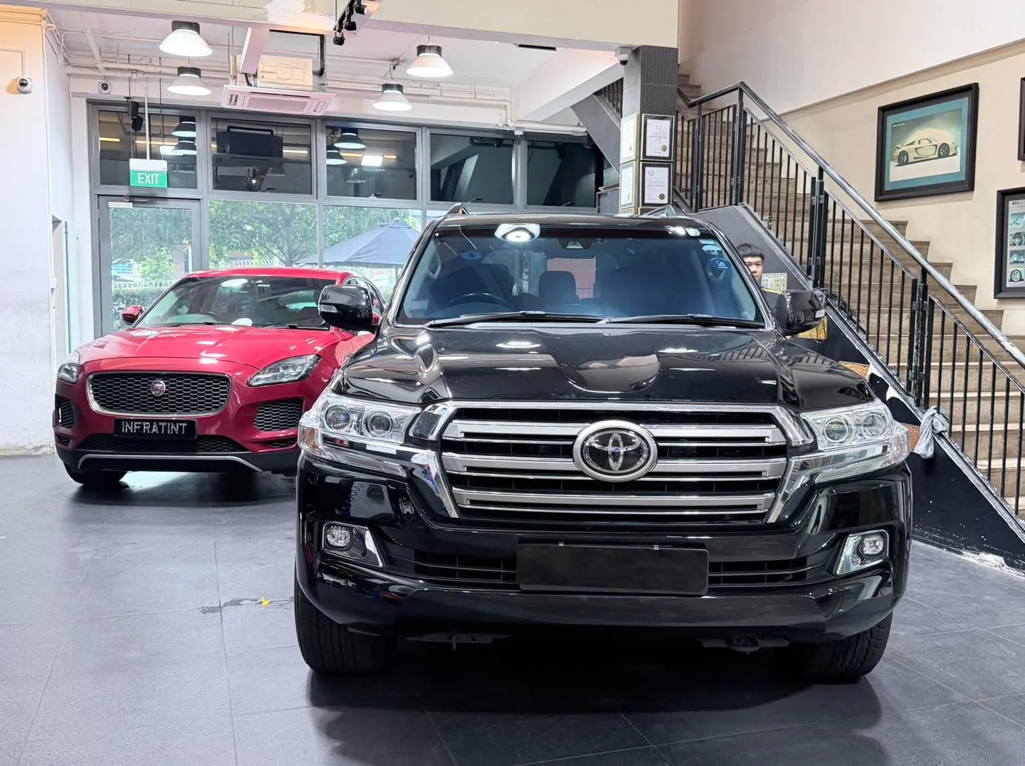 A red Jaguar E-Pace and a black Toyota Land Cruiser inside the workshop.