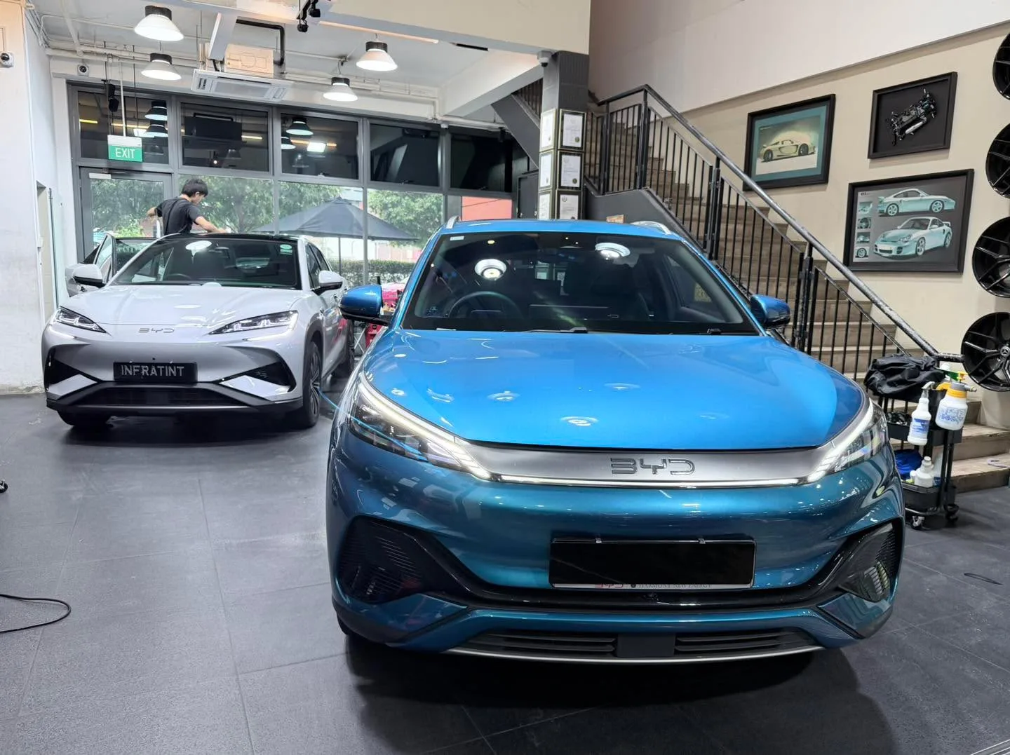 A turquoise BYD Sealion 7 sedan with staff applying window tint.