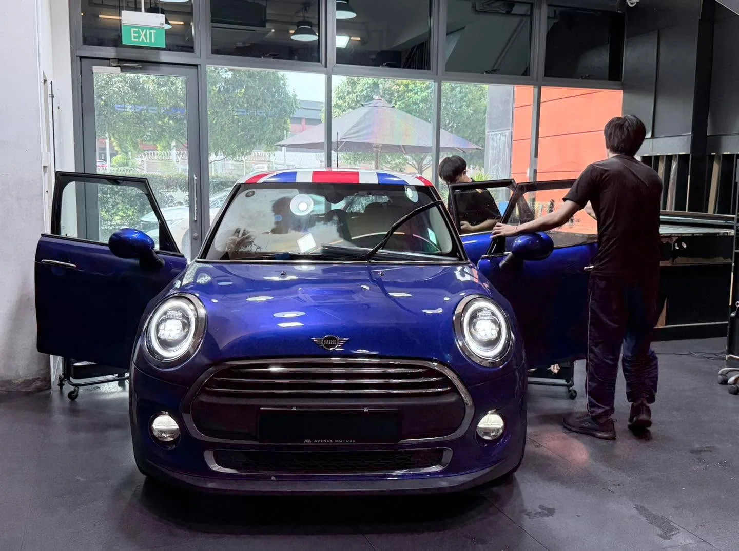 A royal blue Mini One hatchback with open doors during window tinting.