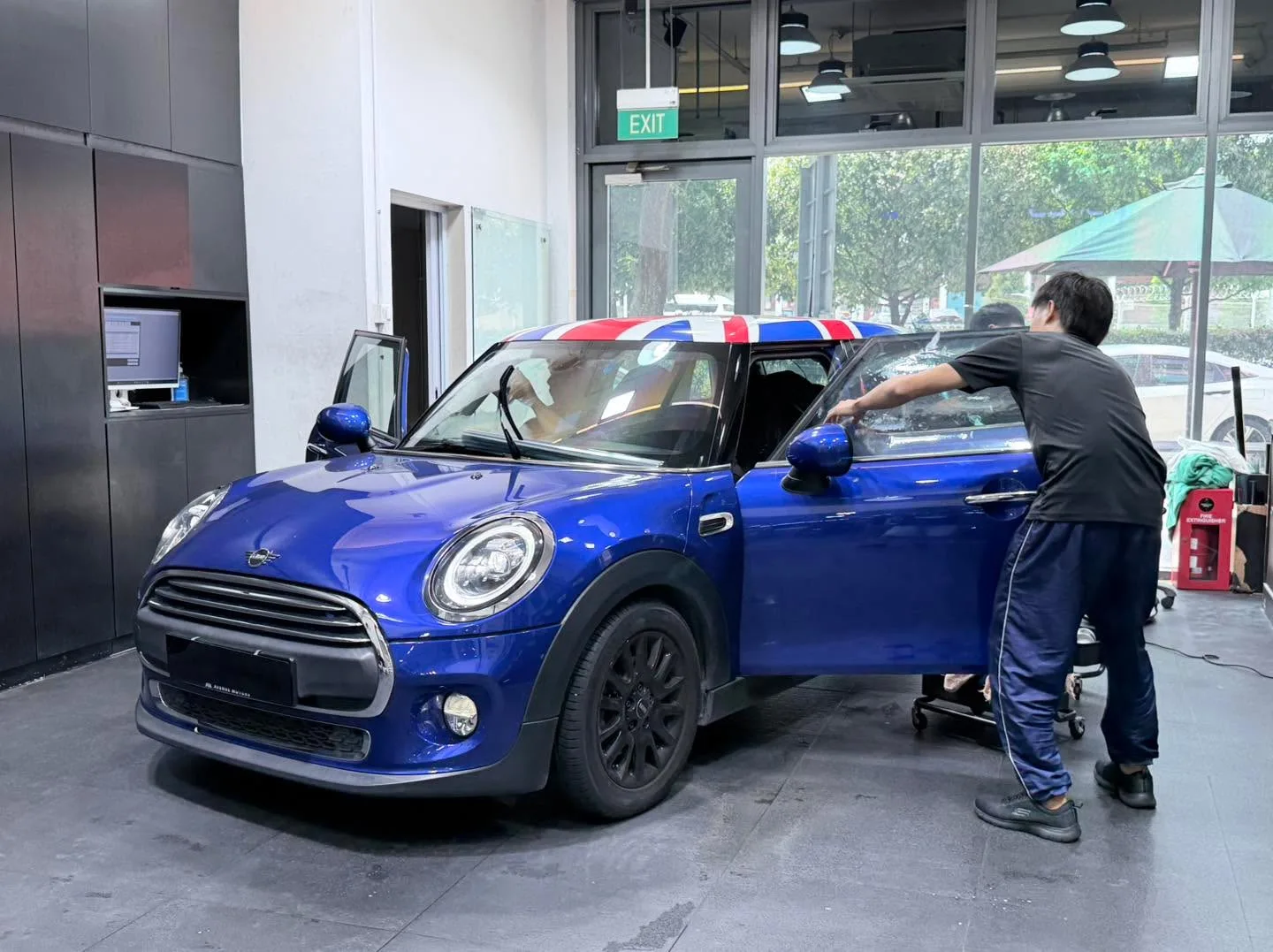 A royal blue Mini One hatchback with open doors during window tinting work.