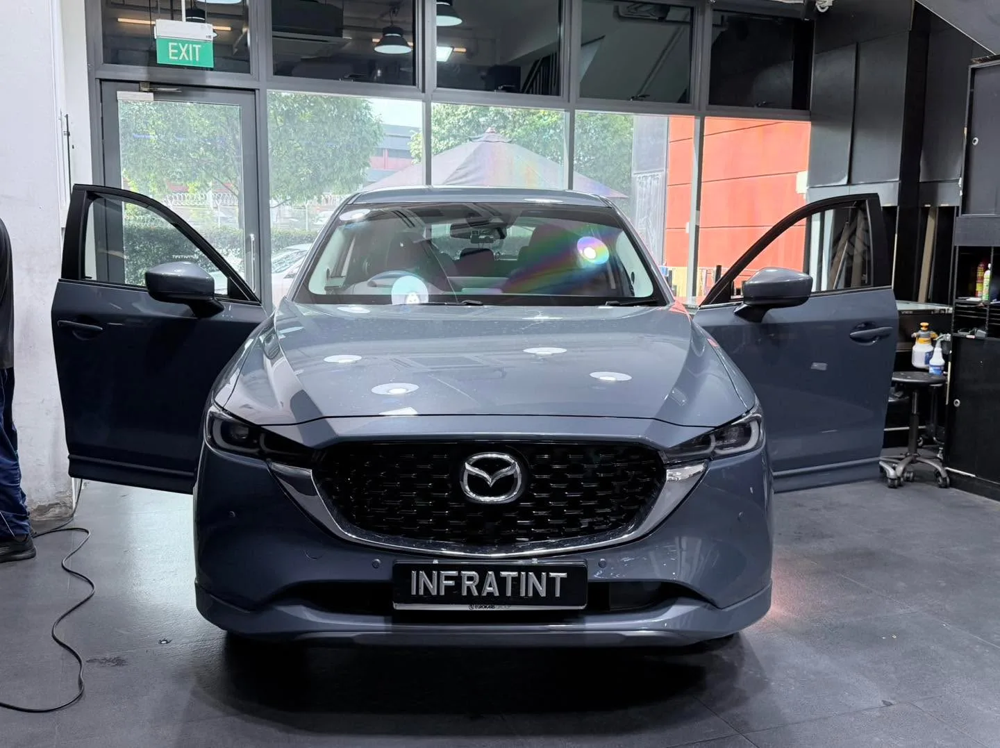 A dark grey Mazda CX-5 SUV with open doors in the workshop.