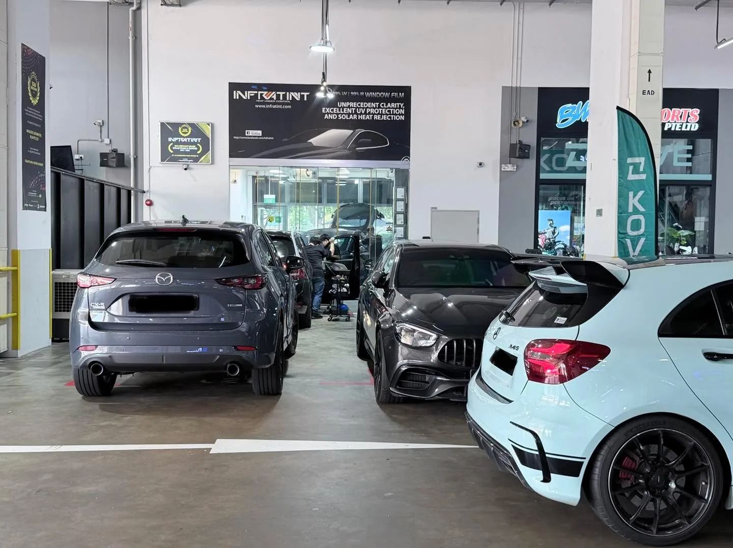 A grey Mazda CX-5, a black Kia Cerato and a white compact car inside the showroom.