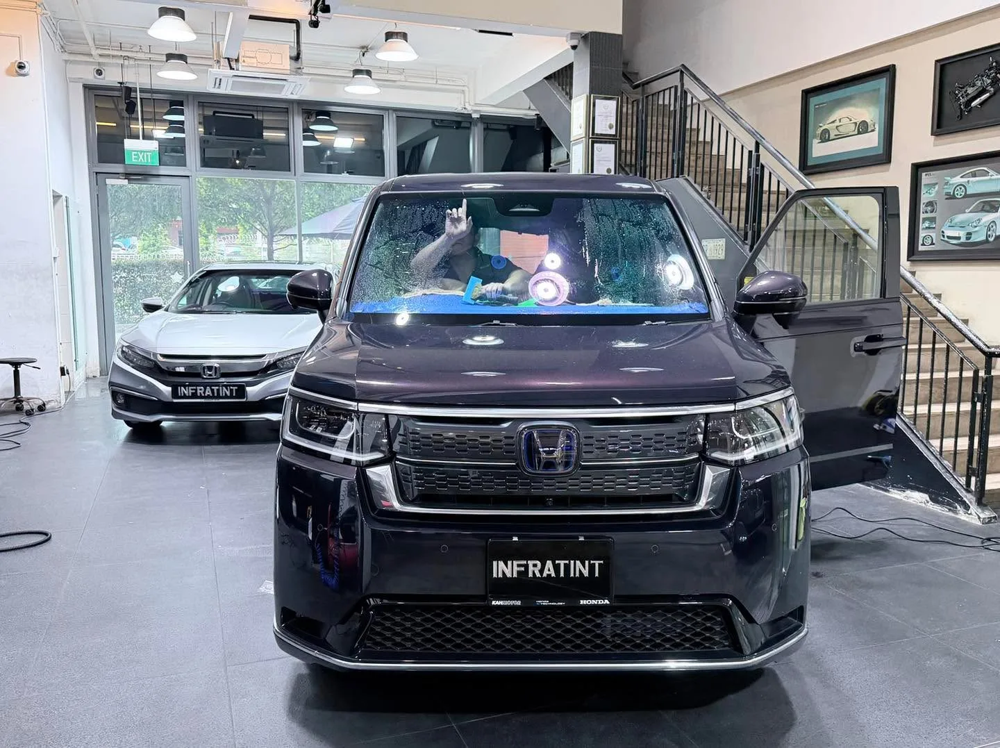 A black Honda SUV with its large windscreen visible, parked indoors at Infratint workshop.