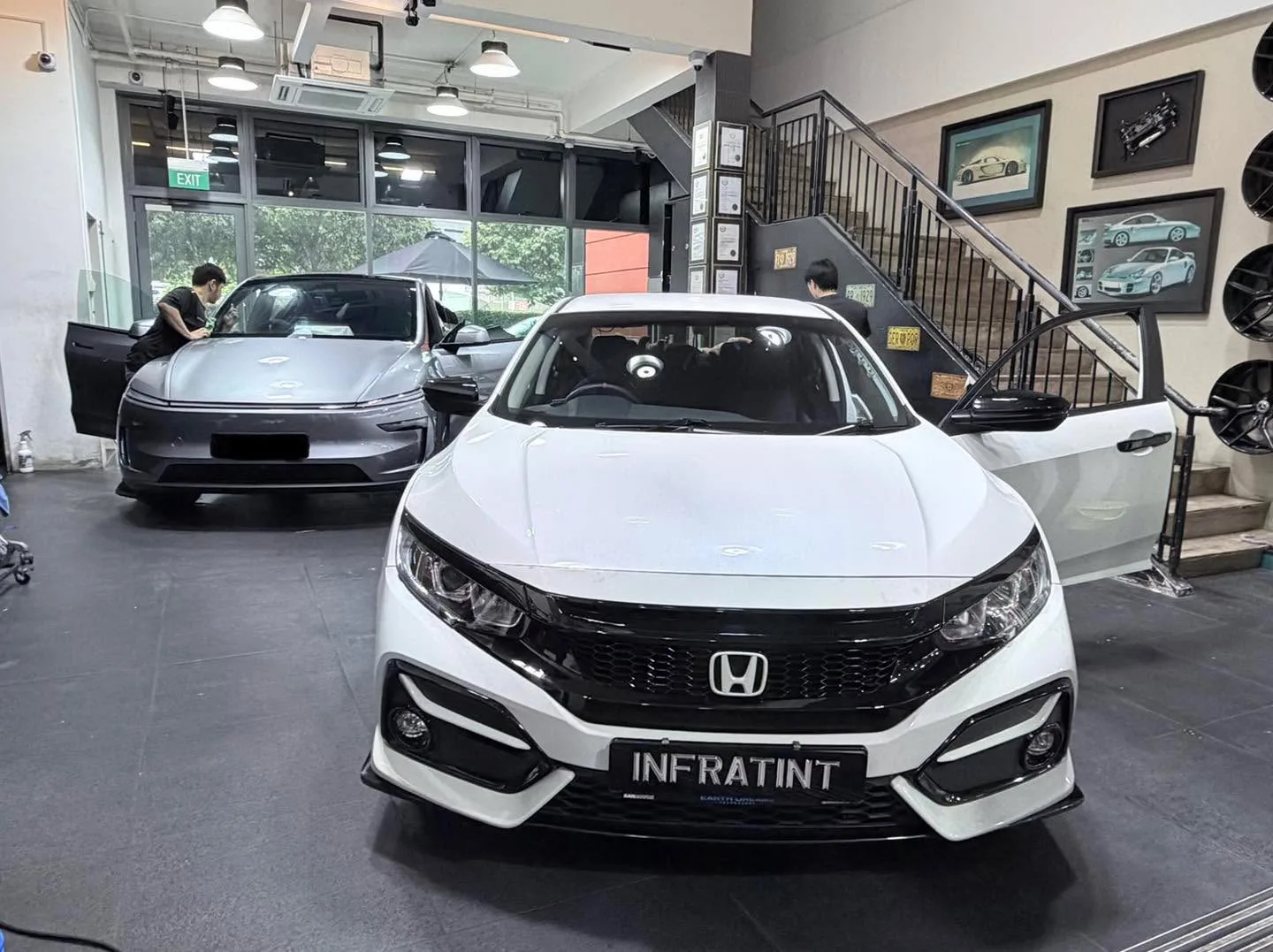 A white Honda sedan with Infratint licence plate, parked indoors with other cars visible.