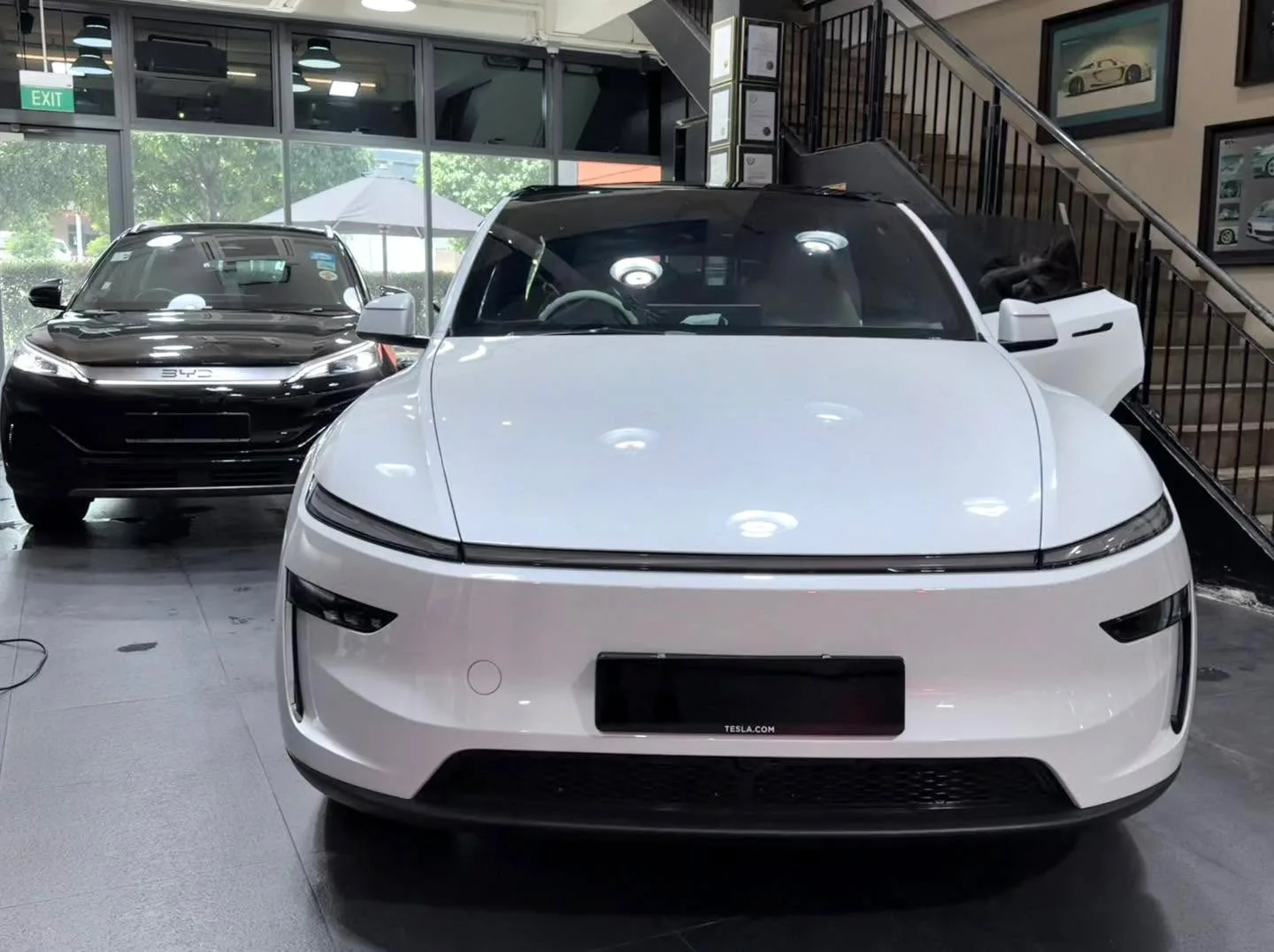 A white Tesla saloon with the bonnet open, doors open, positioned in the workshop.