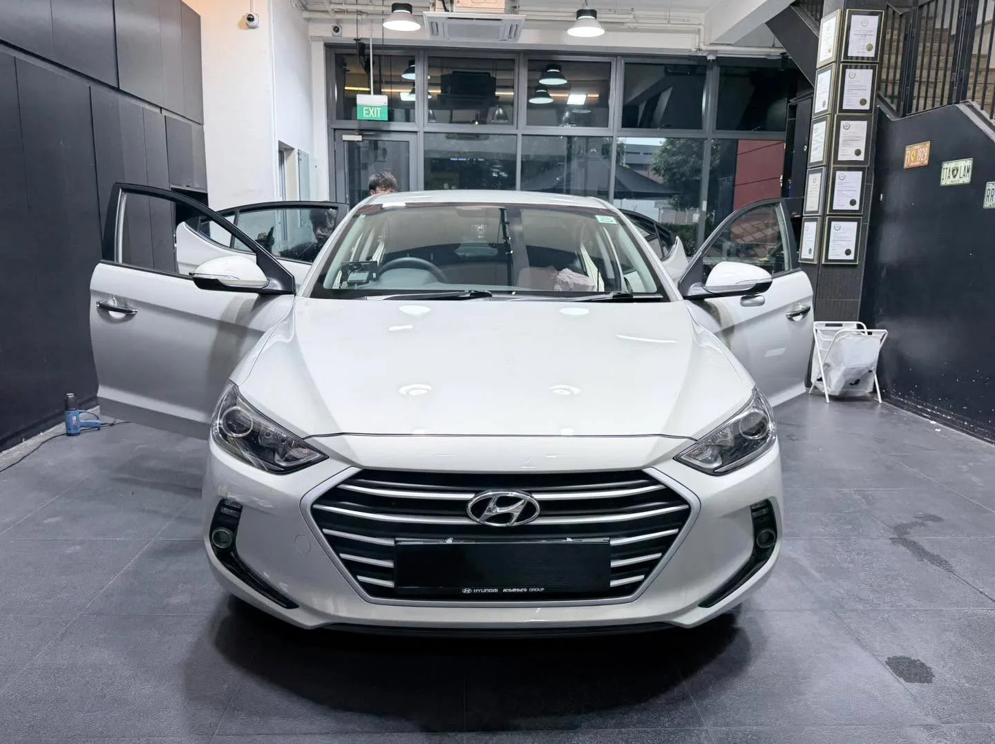 A white Hyundai saloon with doors open inside the workshop.