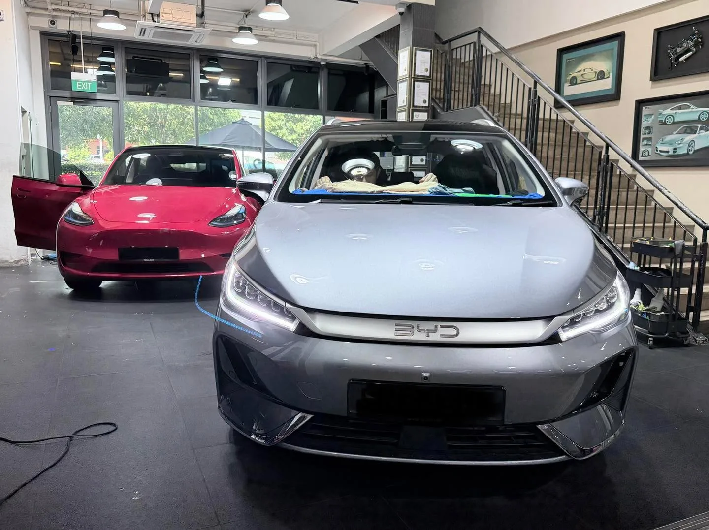 Silver Mazda 3 sedan next to grey BMW sedan with tint being applied.