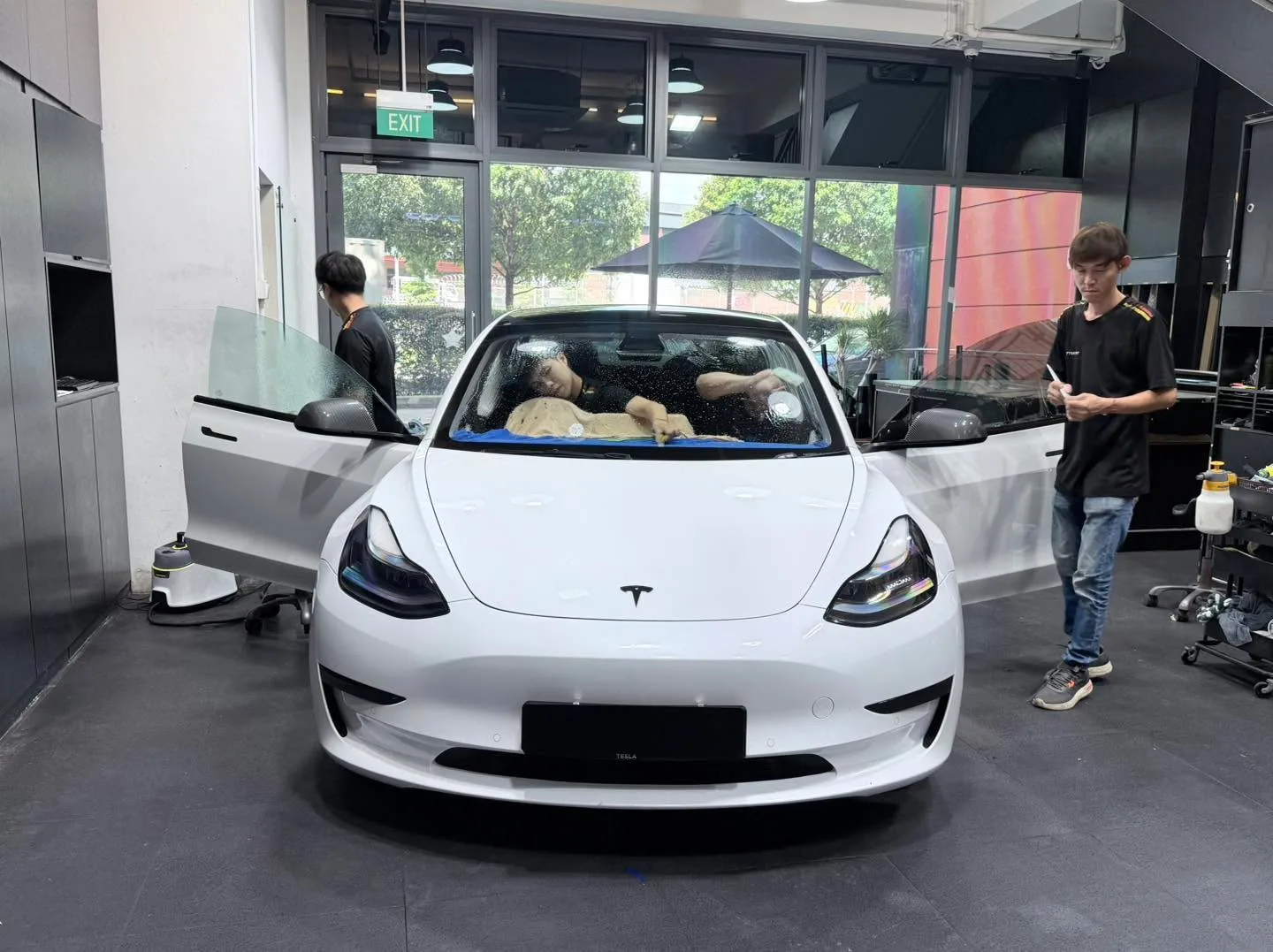A white Tesla sedan parked indoors during window tint application.