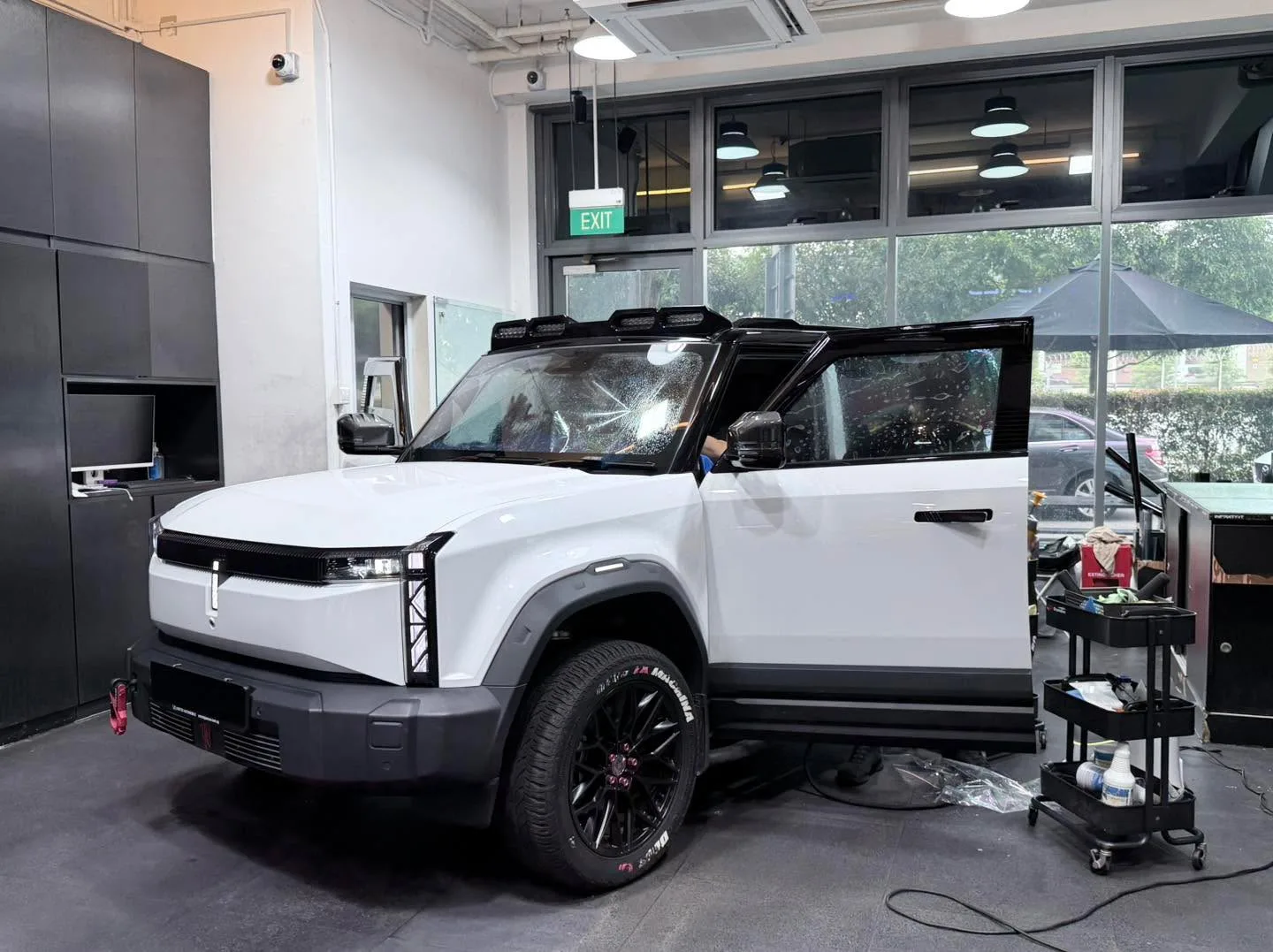 A white Rivian R1T parked indoors with tinting in progress.