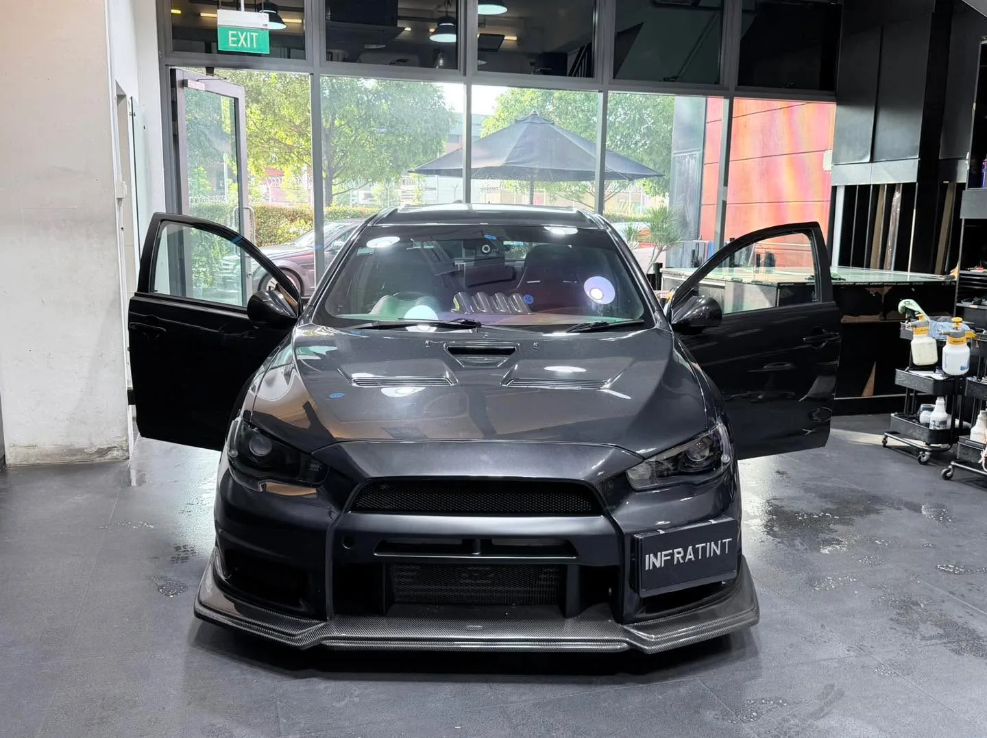 A black Mitsubishi Lancer Evolution 10 with doors open, showing the characteristic front grille and aggressive styling.
