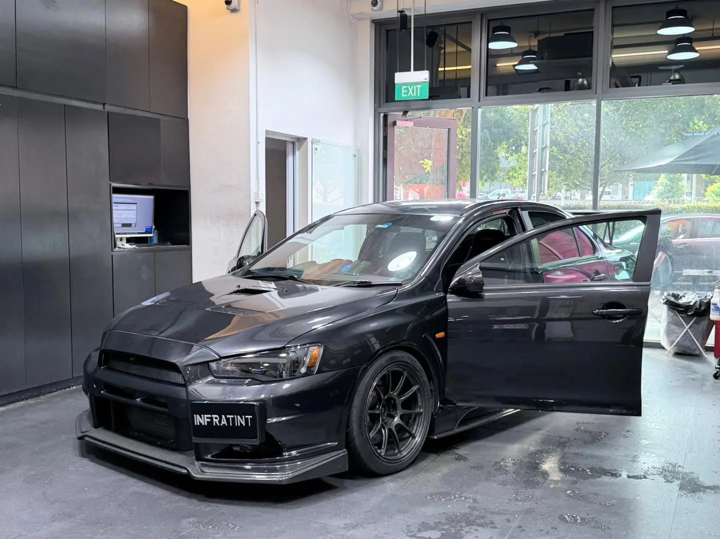 A black Mitsubishi Lancer Evolution 10 with door open during window tinting work.