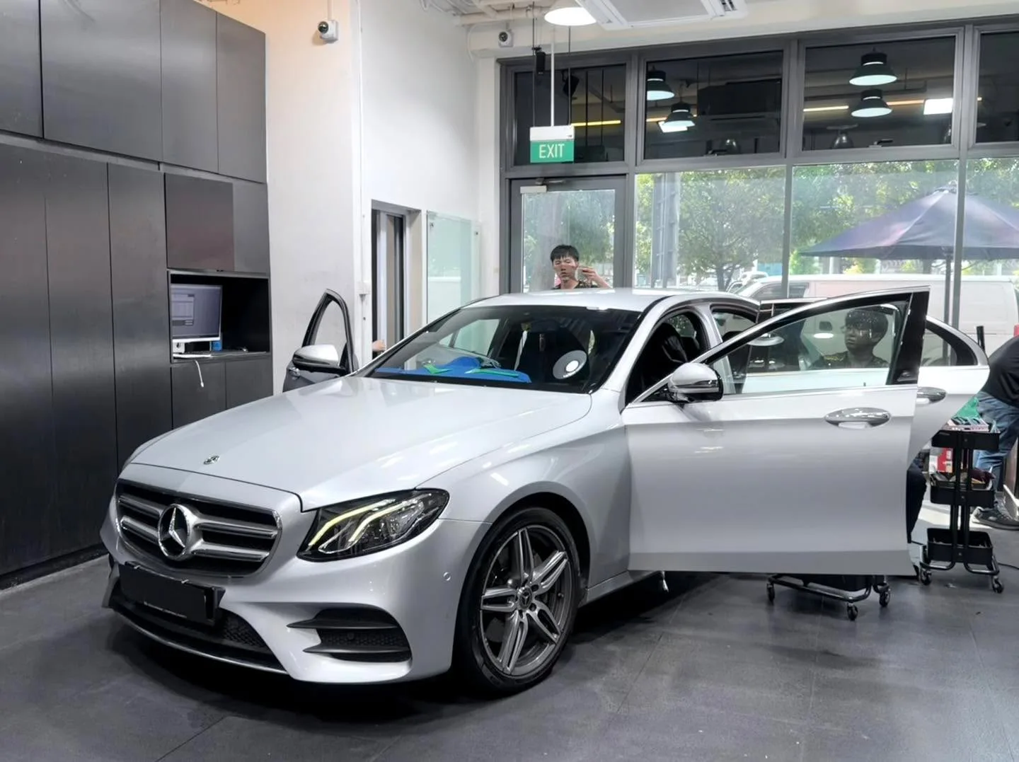 A silver Mercedes-Benz sedan with doors open in the workshop.