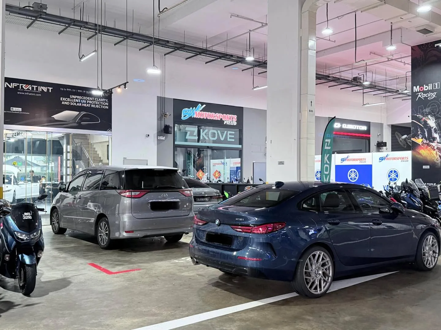 A silver SUV and dark blue sedan parked in a workshop with tinted windows visible.